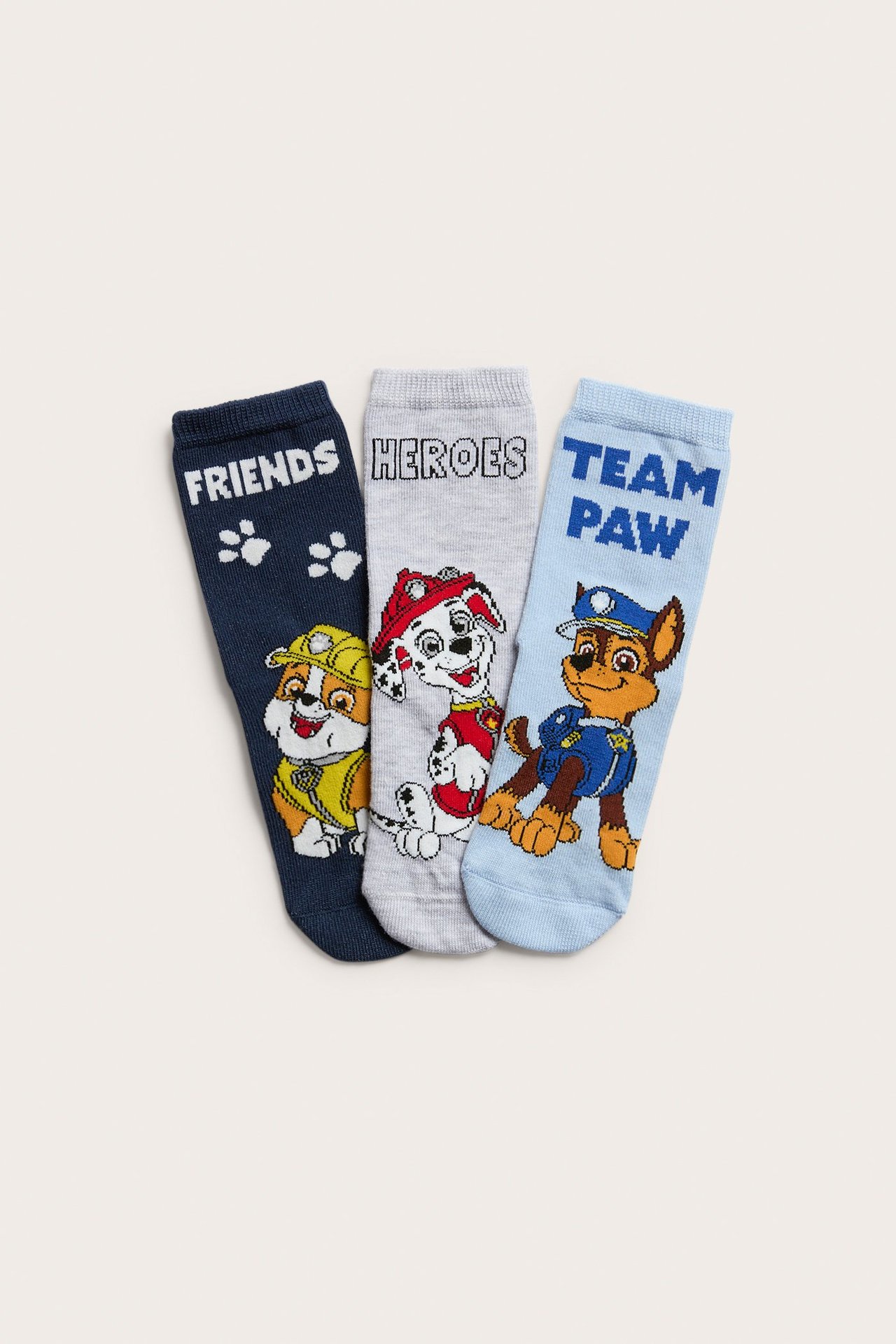 Framsidan av ett 3-pack barnstrumpor: mörkblå, ljusgrå och ljusblå med Paw Patrol-tryck.