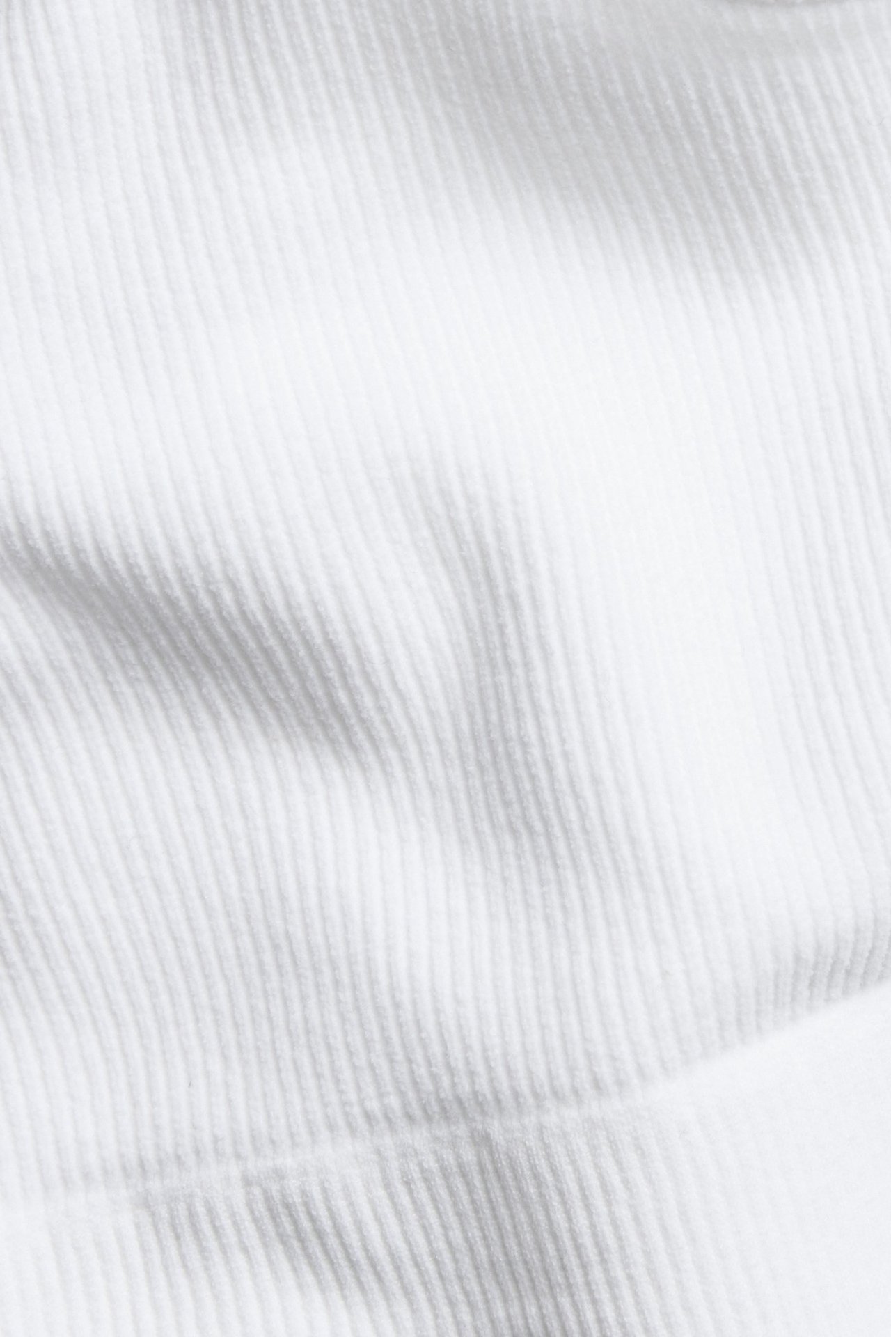 Zbliżenie białej, prążkowanej, bezszwowej tkaniny topu.