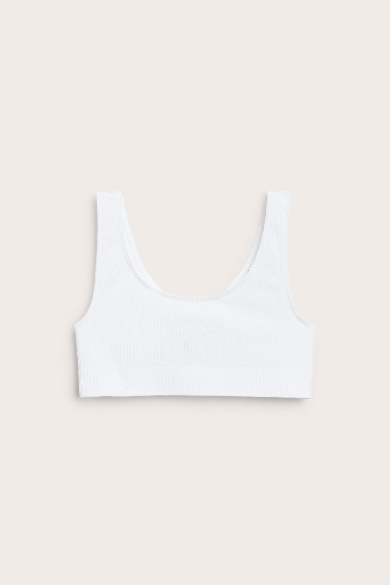 Widok z przodu: biały, prążkowany, bezszwowy top crop z szerokimi ramiączkami.