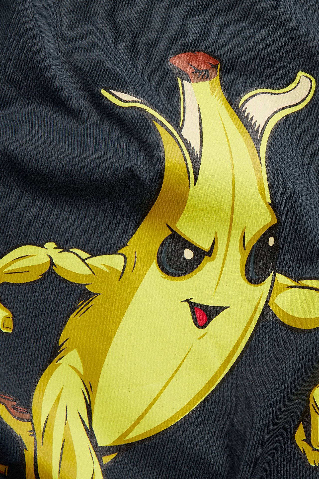 Lähikuva lasten tummansinisestä puuvillaisesta T-paidasta, jossa on keltainen lihaksikas banaani Fortnite-kuvio.