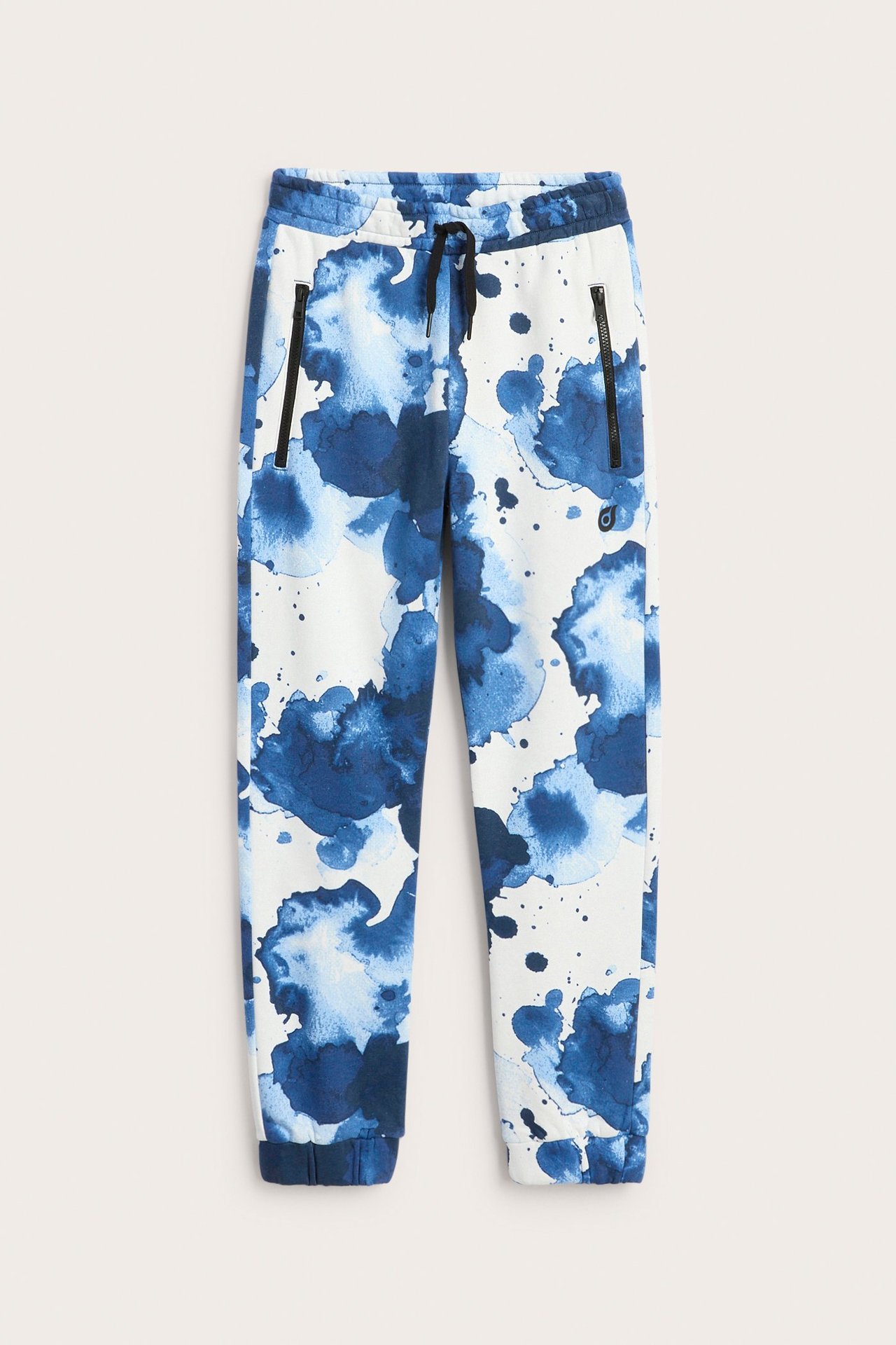 Widok z przodu: Ecru dresowe spodnie z niebieskim wzorem akwarelowym, sznurkiem i czarnymi kieszeniami.
