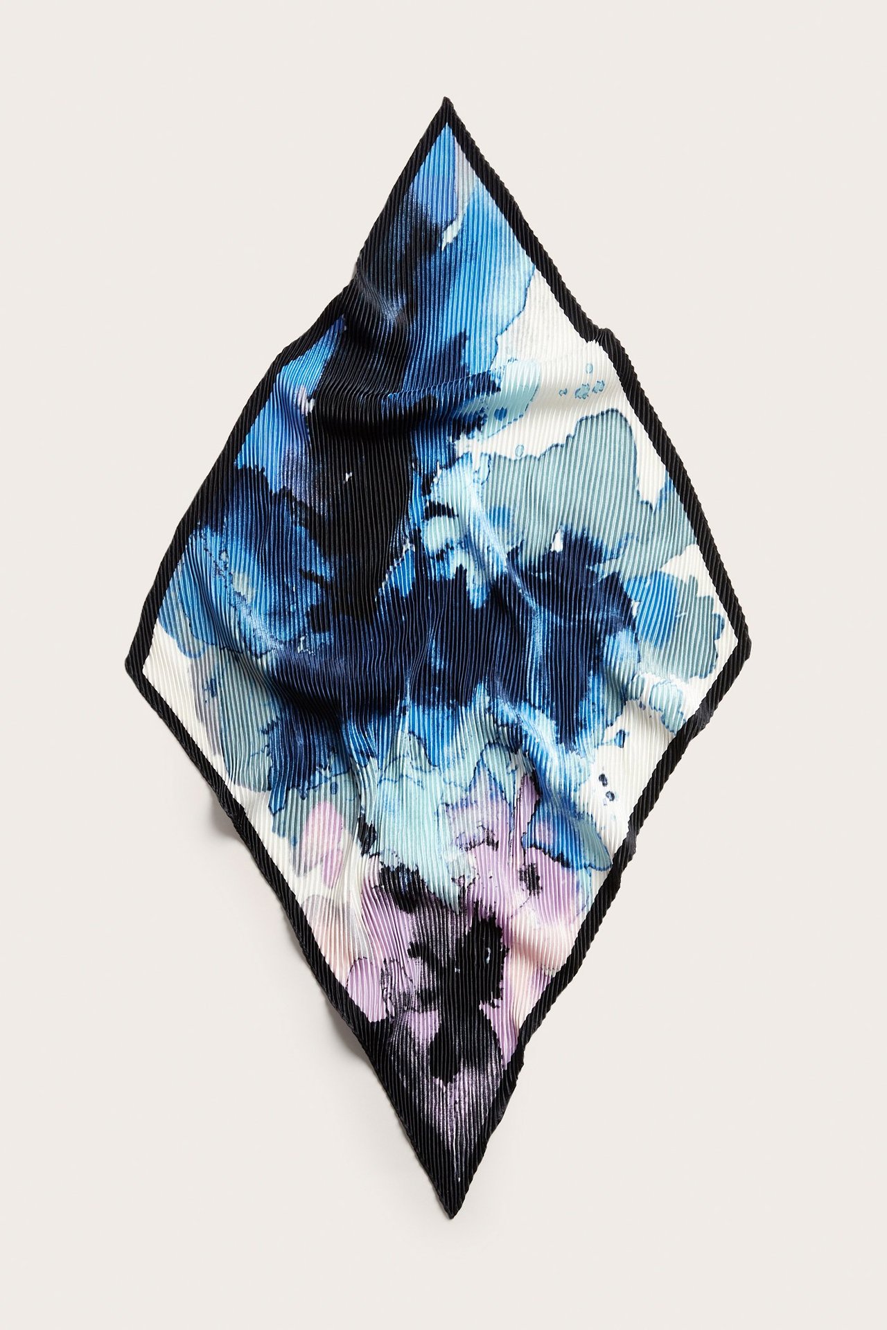 Uppifrån sett en fyrkantig plisserad polyesterscarf med blått, ljusblått och lila akvarellmönster.