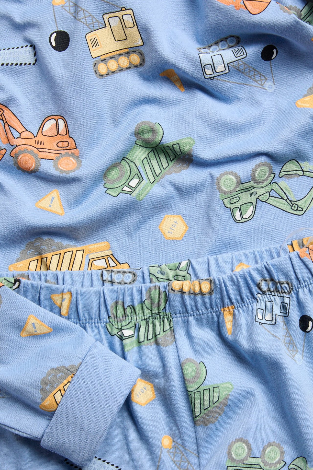 Lähikuva vaaleansinisestä puuvillapyjamasta, jossa on rakennusajoneuvokuvio ja joustava vyötärö.