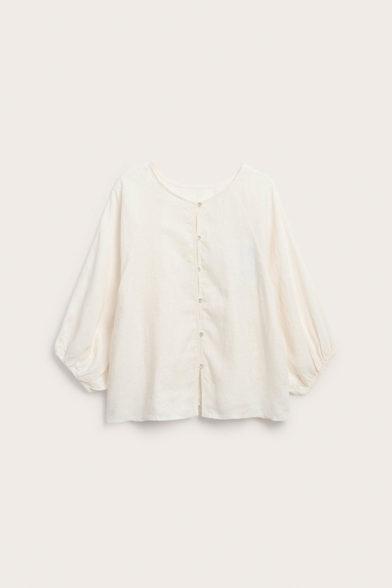 Biała lniana bluzka z okrągłym dekoltem, guzikami, szerokimi rękawami raglanowymi ze ściągaczami.