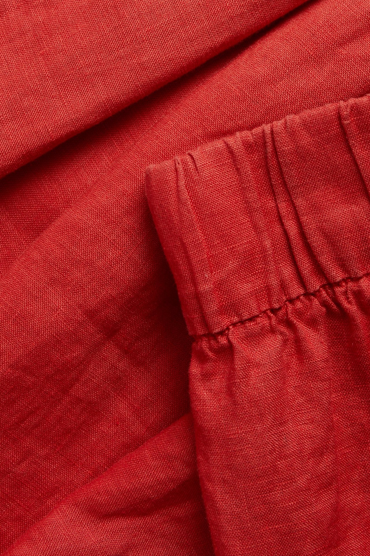 Lähikuva punaisista pellavaista polvipituisista shortseista, joissa on joustava vyötärö.