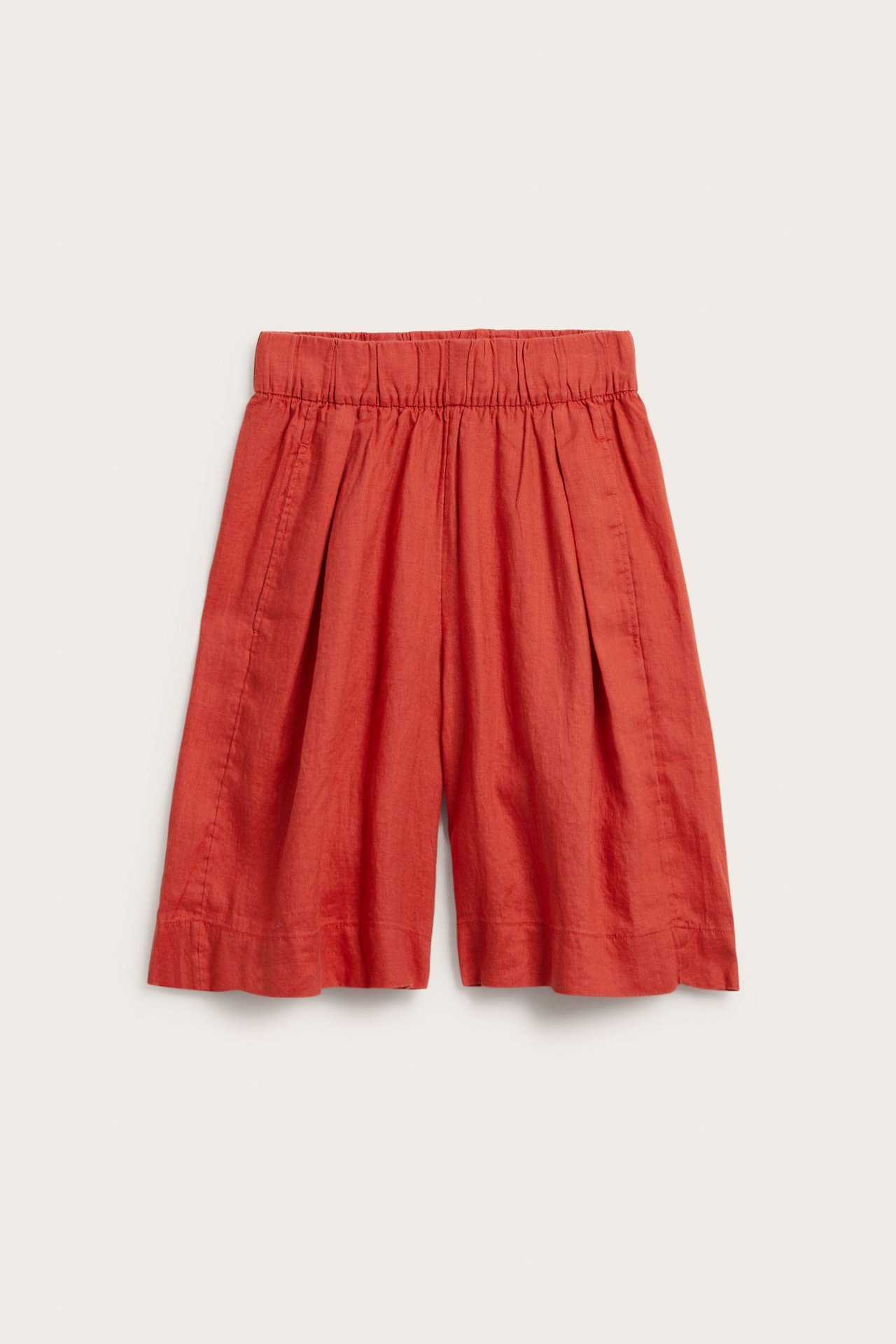 Edestä kuvatut punaiset pellavashortsit, joissa on joustava vyötärö, laskokset ja sivutaskut.