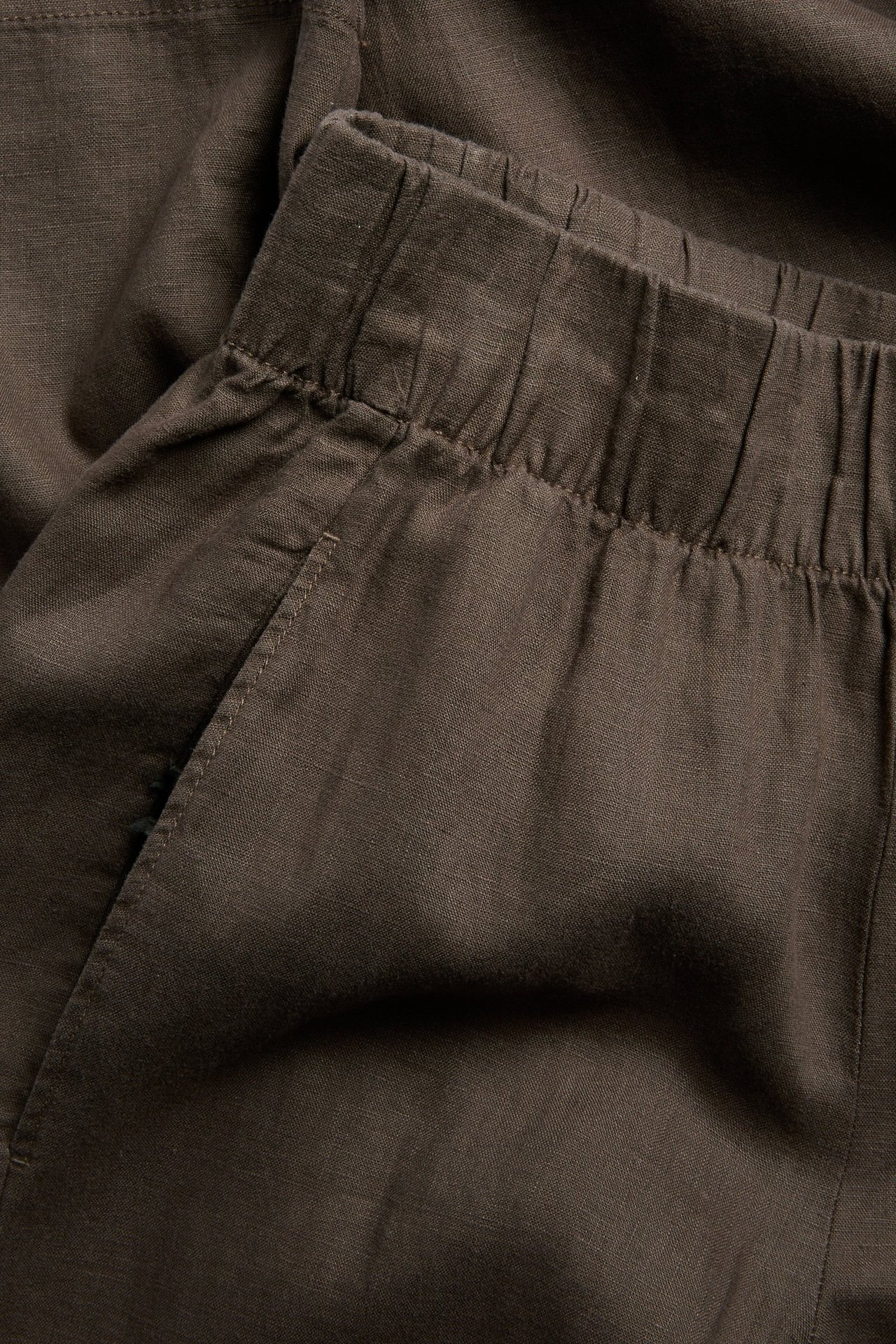 Lähikuva ruskeista pellavaisista pull-on-housuista, joissa on joustava vyötärö ja sivutasku.