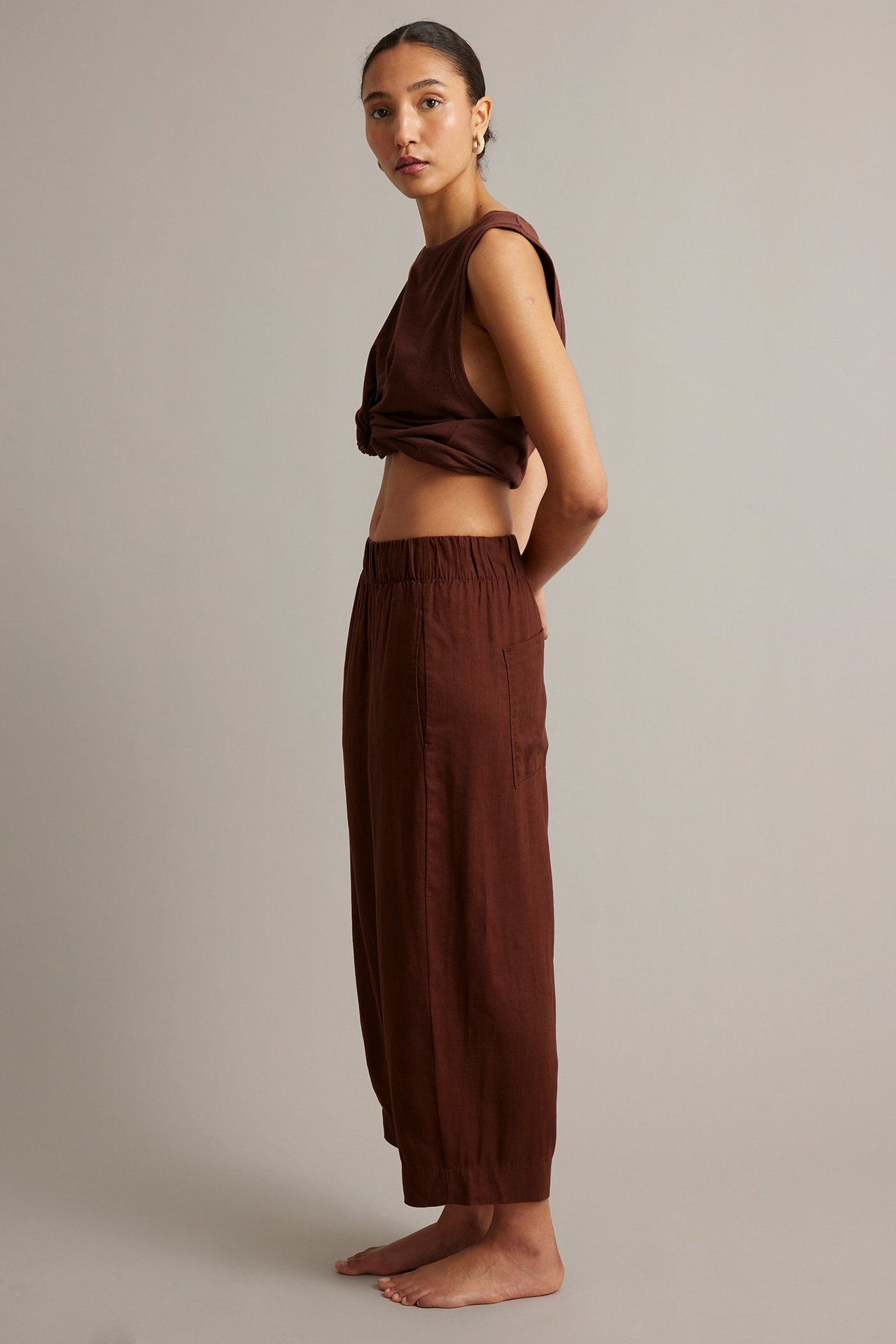 Sivukuva: nainen viininpunaisissa barrel-fit pellavahousuissa joustovyötäröllä ja yhteensopivassa topissa.