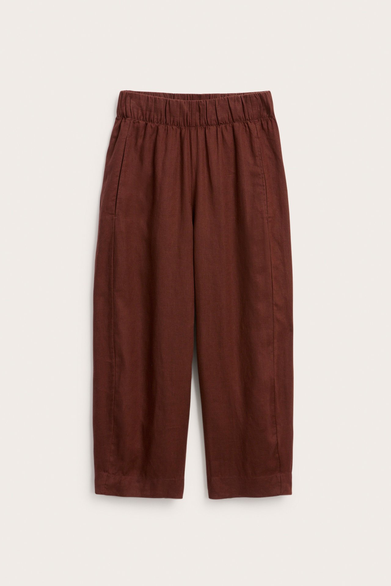 Widok z przodu bordowych, lnianych spodni typu barrel fit z elastyczną talią i kieszeniami.