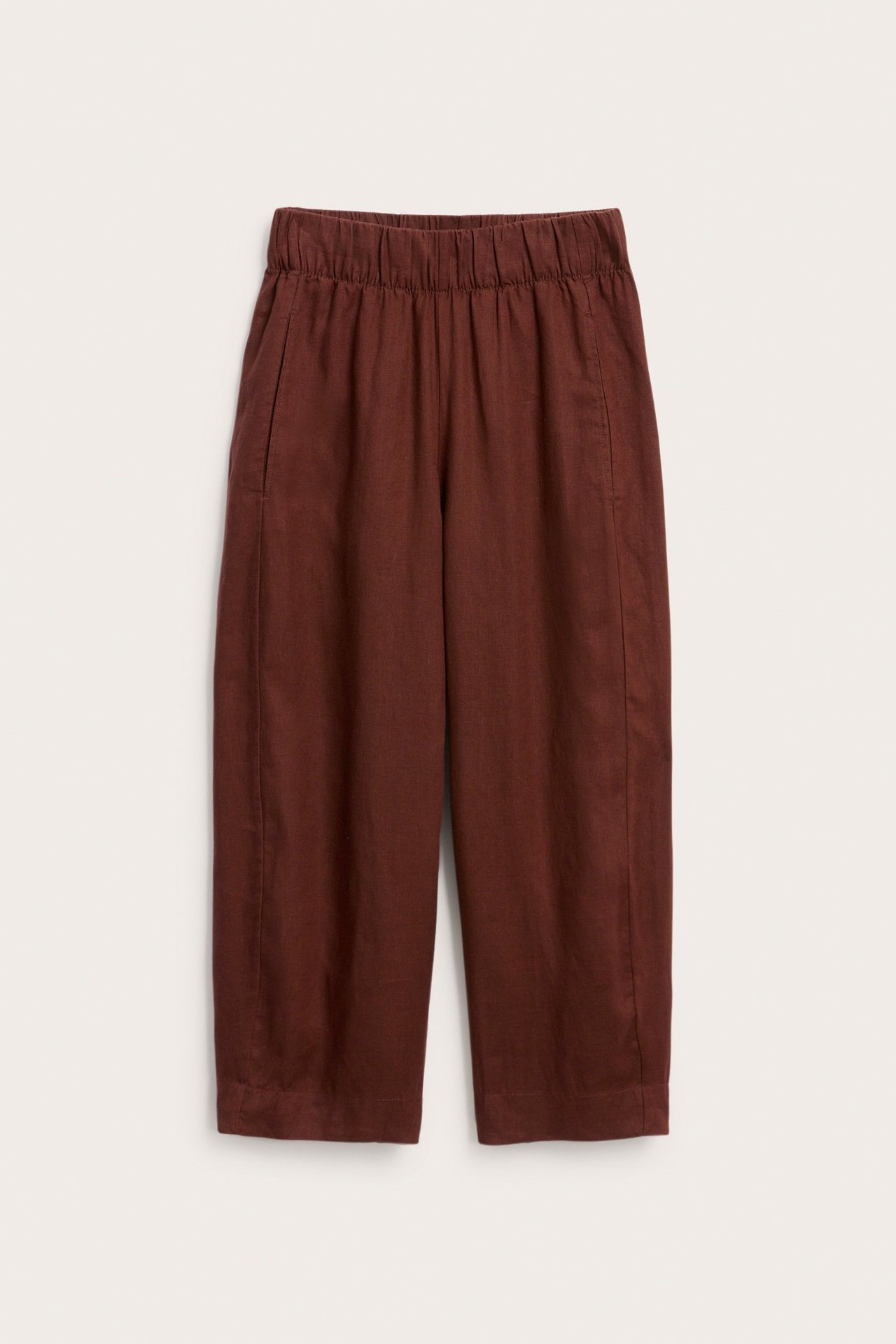 Widok z przodu bordowych, lnianych spodni typu barrel fit z elastyczną talią i kieszeniami.