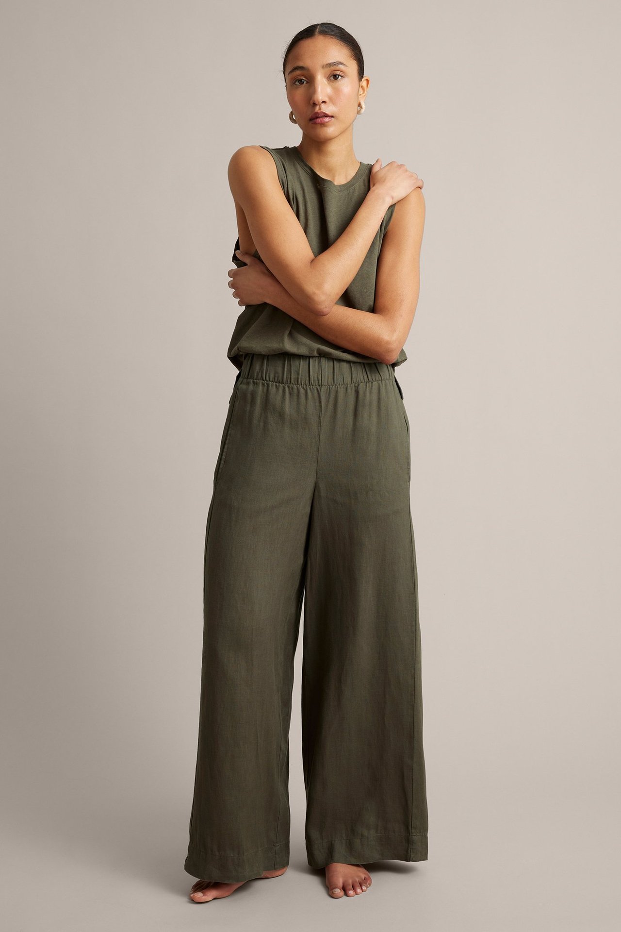 Frontbilde: kvinne i khakigrønn vid linbukse med strikk i midjen og matchende ermeløs topp.