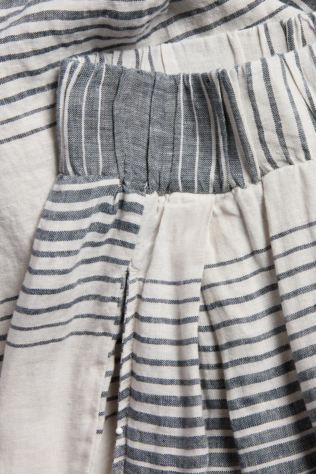 Nærbilde av mørkeblå- og naturhvitstripete vide linbukser med strikk i livet og motlegg.