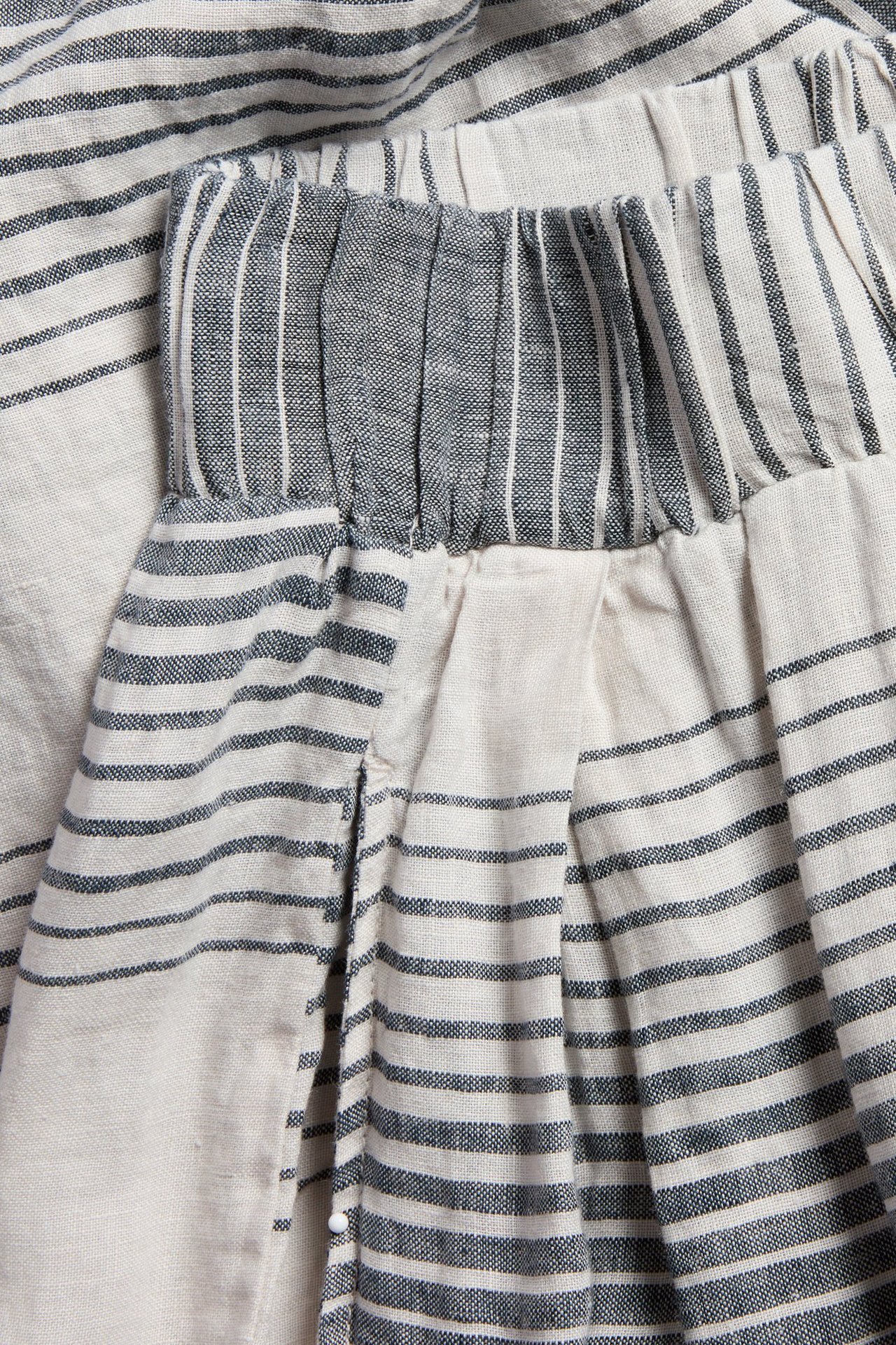 Närbild av mörkblå- och naturvitrandiga vida linnebyxor med resårlinning och motveck.