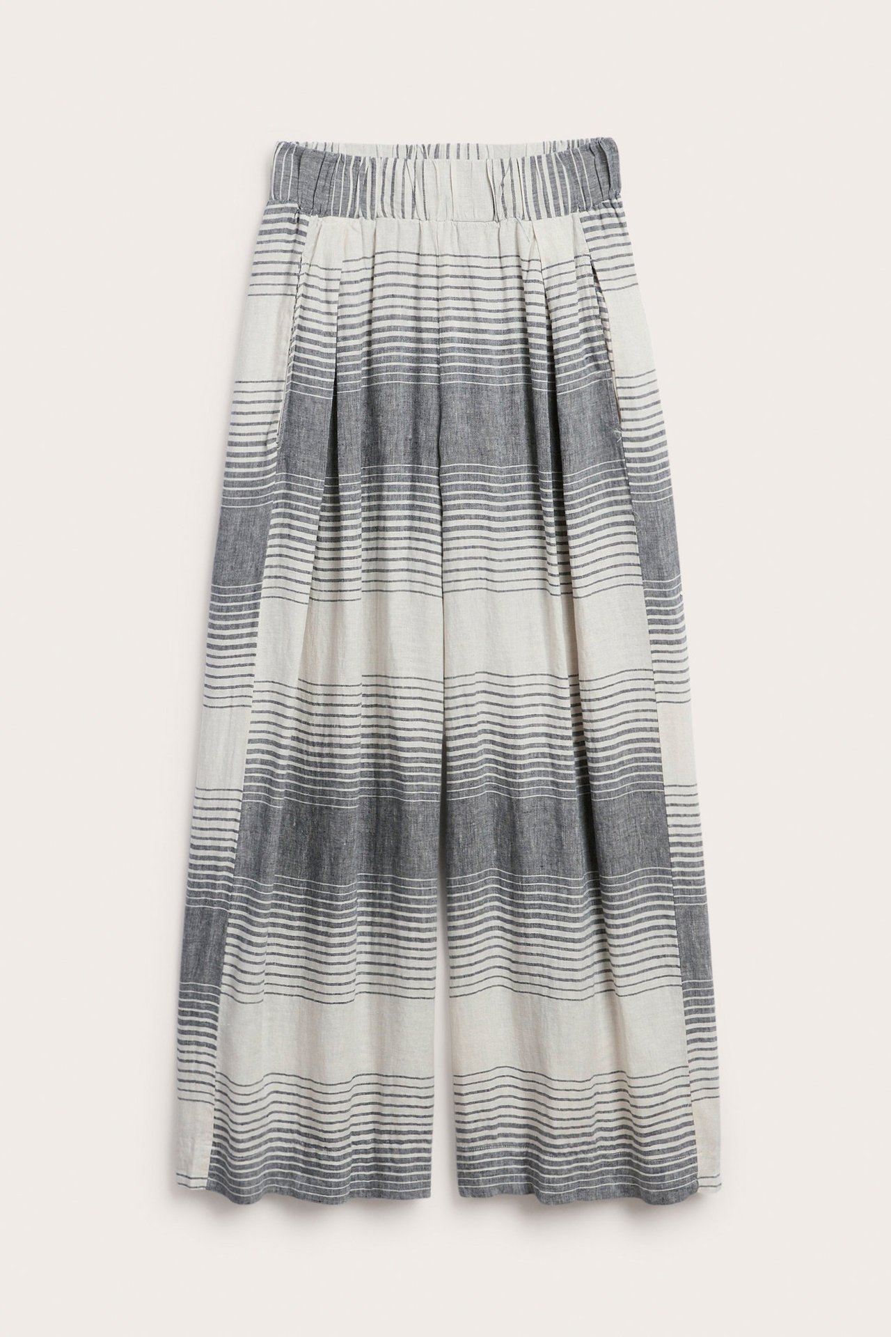 Frontvisning, dame, vide stripete linbukser med strikk i livet i off-white og mørkeblått.
