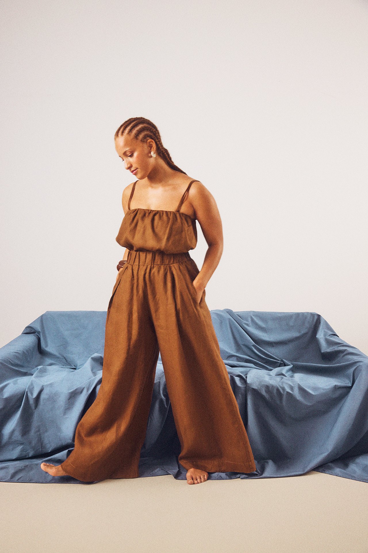 Forfra, kvinne i brune vide linbukser med strikk i midjen og en matchende brun linnetopp.