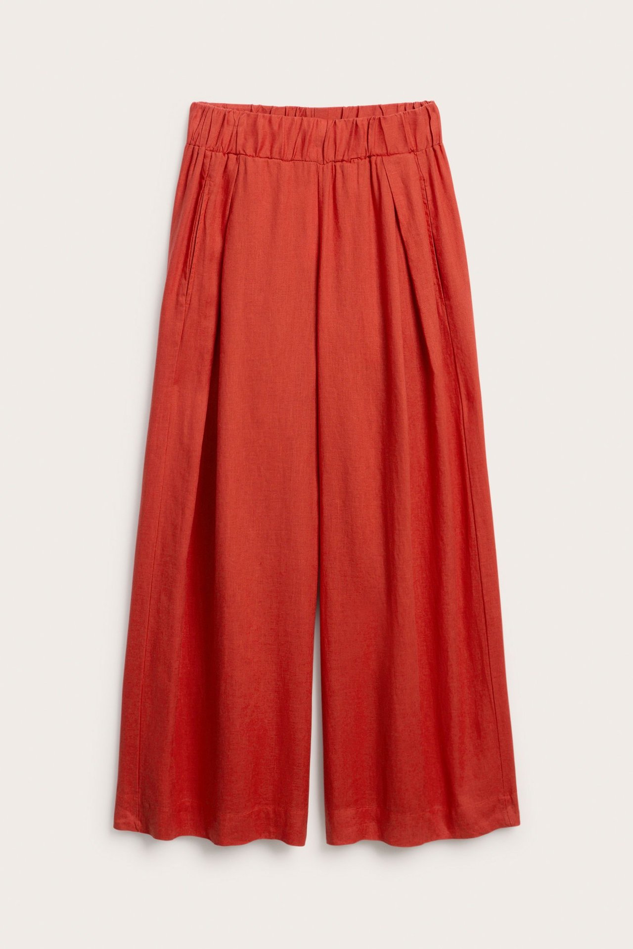 Frontvy av röda linnebyxor med vida ben, elastisk midja, motveck och sidfickor.