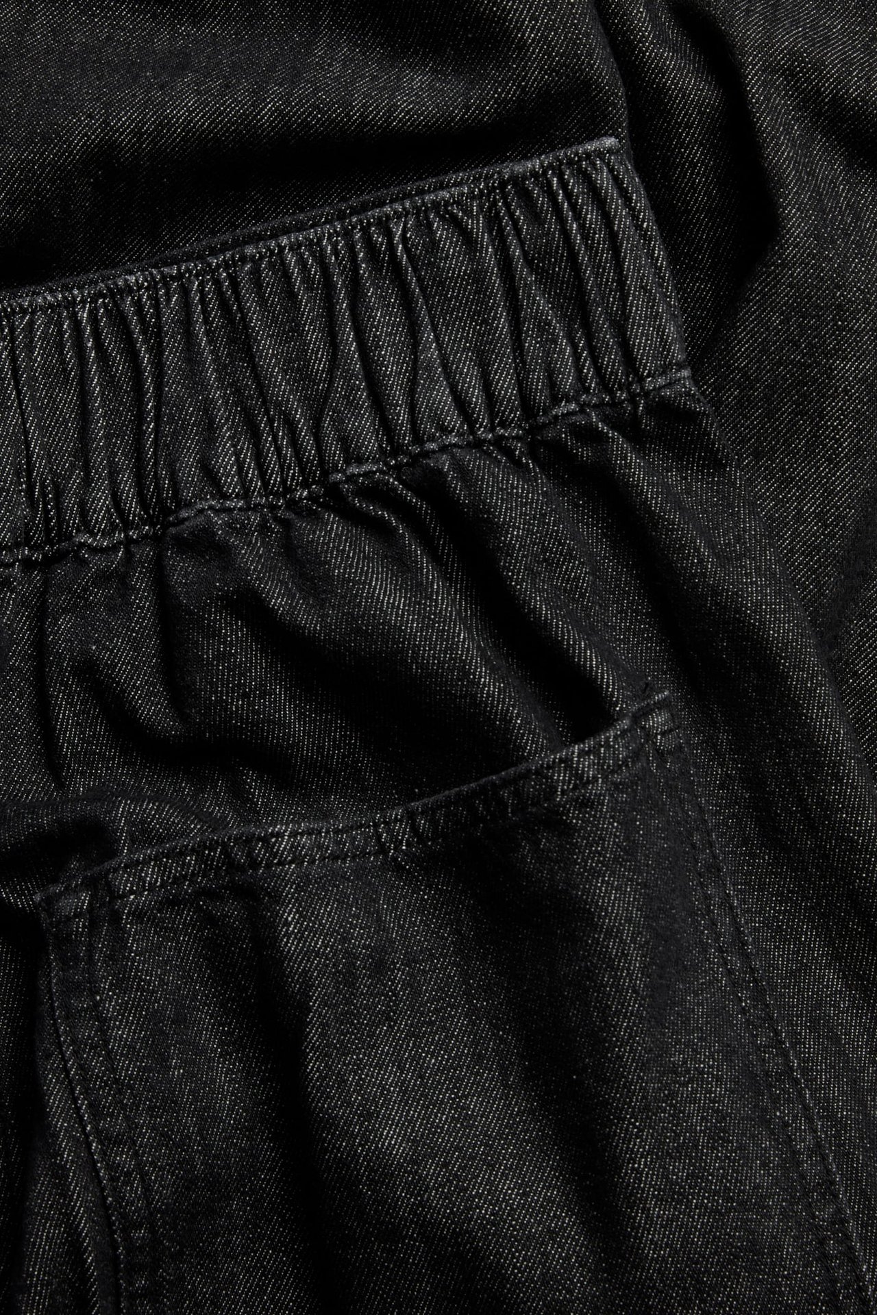 Zbliżenie czarnych jeansów pull-on barrel fit z elastyczną talią i widoczną tylną kieszenią.