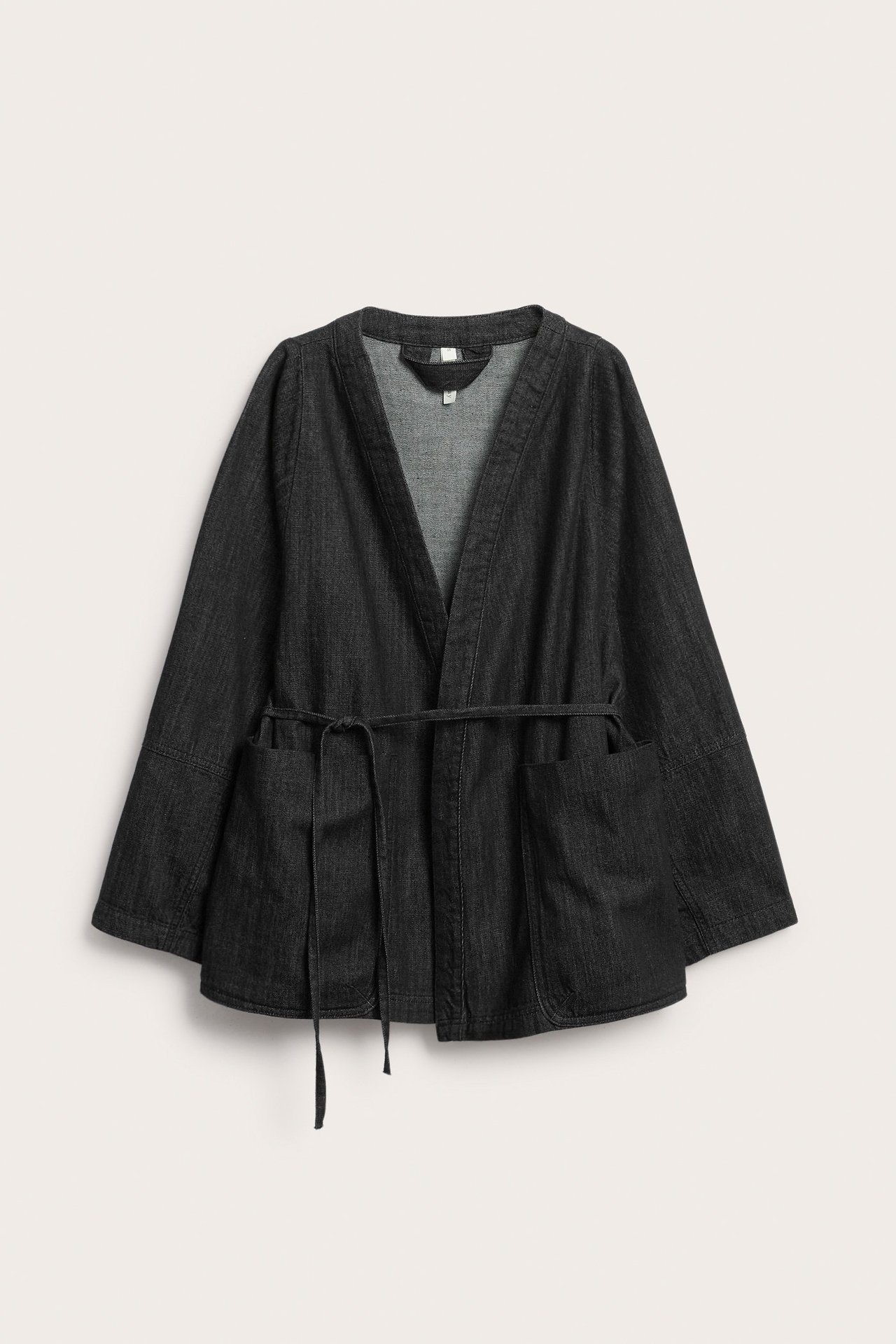 Edestä: Musta denim-kimonotakki V-pääntiellä, leveillä hihoilla, solmimisvyöllä ja suurilla etutaskuilla.