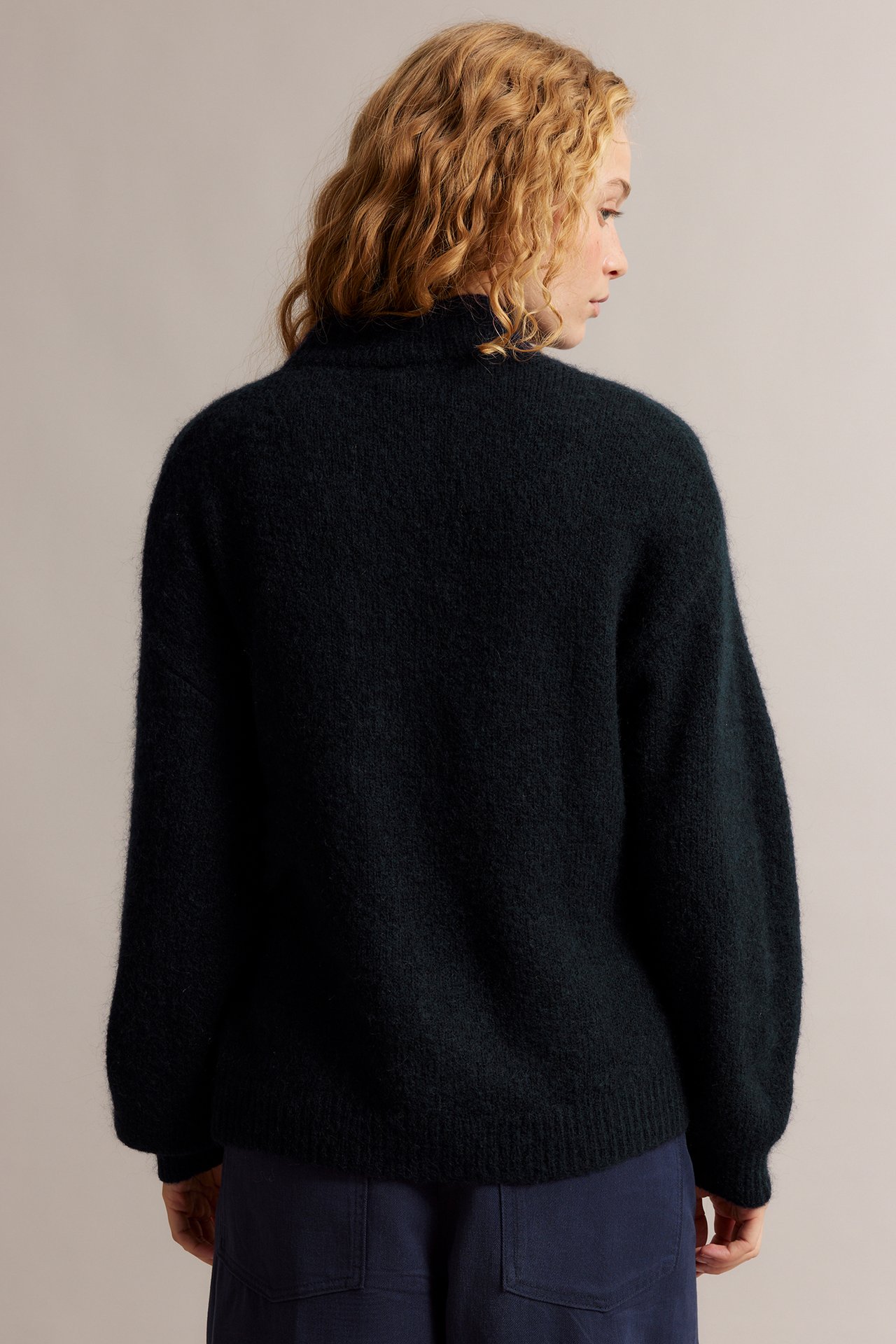 Naisen selkäpuoli tummansinisessä villasekoitekoftassa ja laivastonsinisissä housuissa.