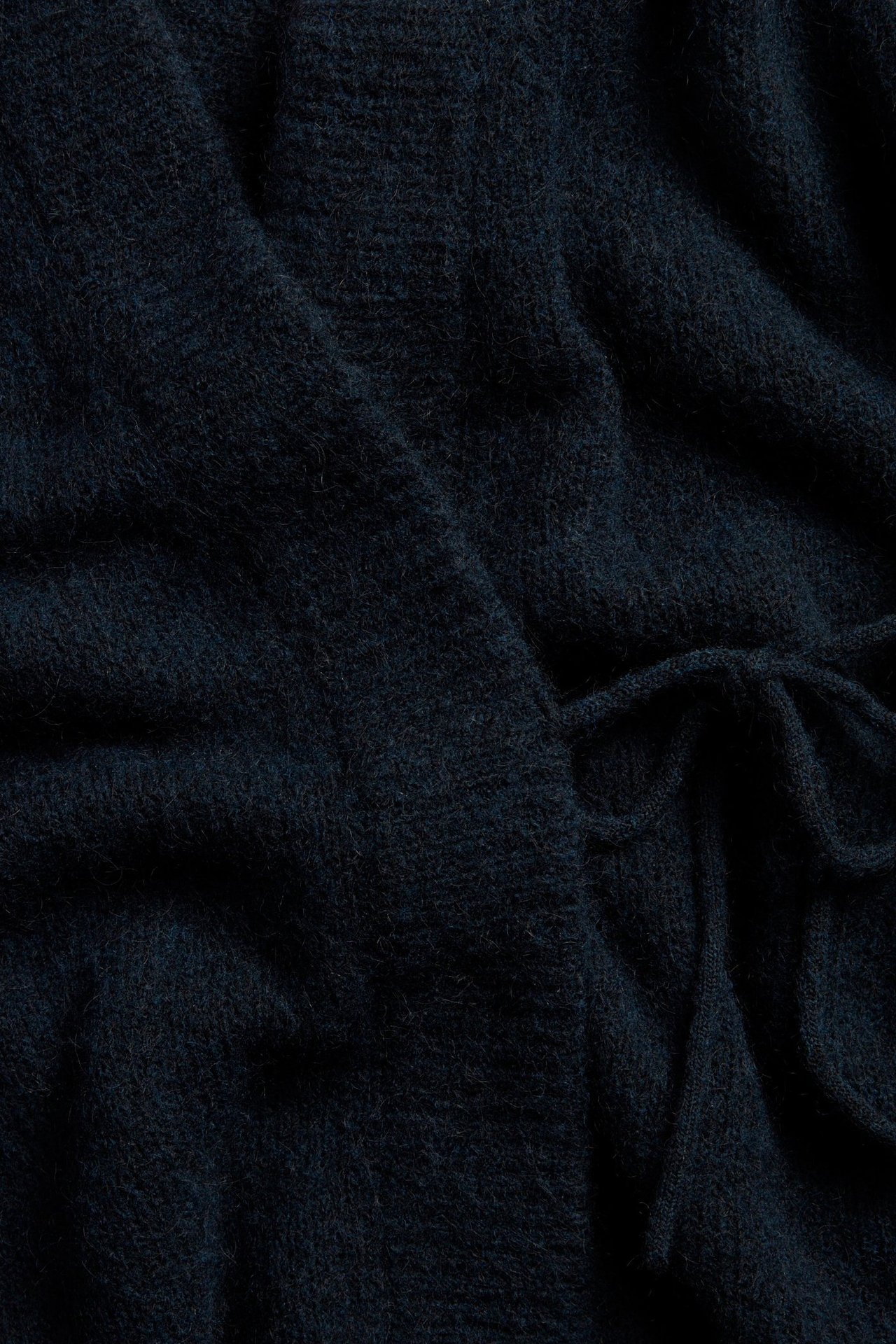 Lähikuva tummansinisestä villasekoitekoftasta, jossa on solmimisnauha.