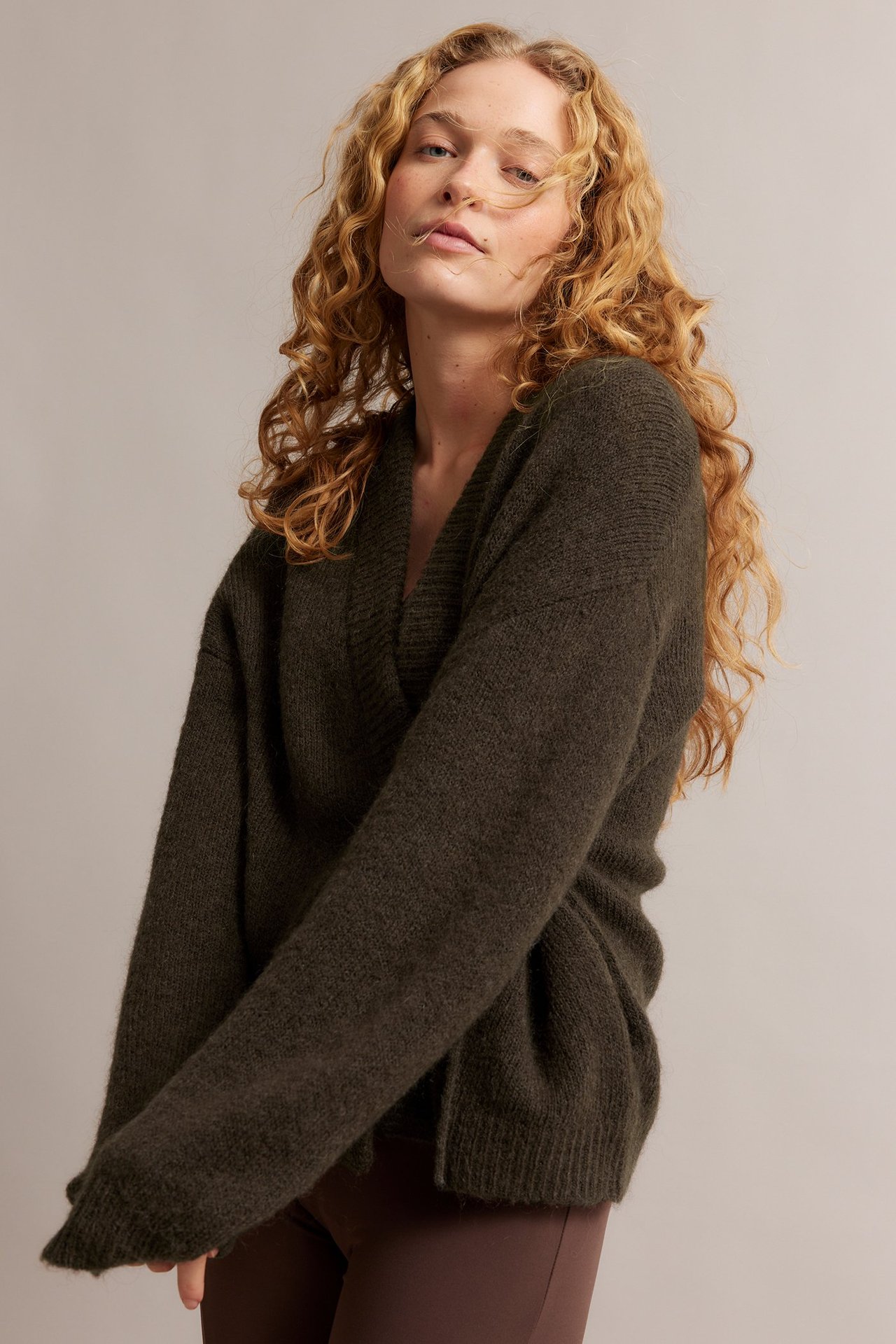 Edestä: nainen tummanruskeassa villasekoitekoftassa solmimisnauhoilla ja ruskeissa housuissa.