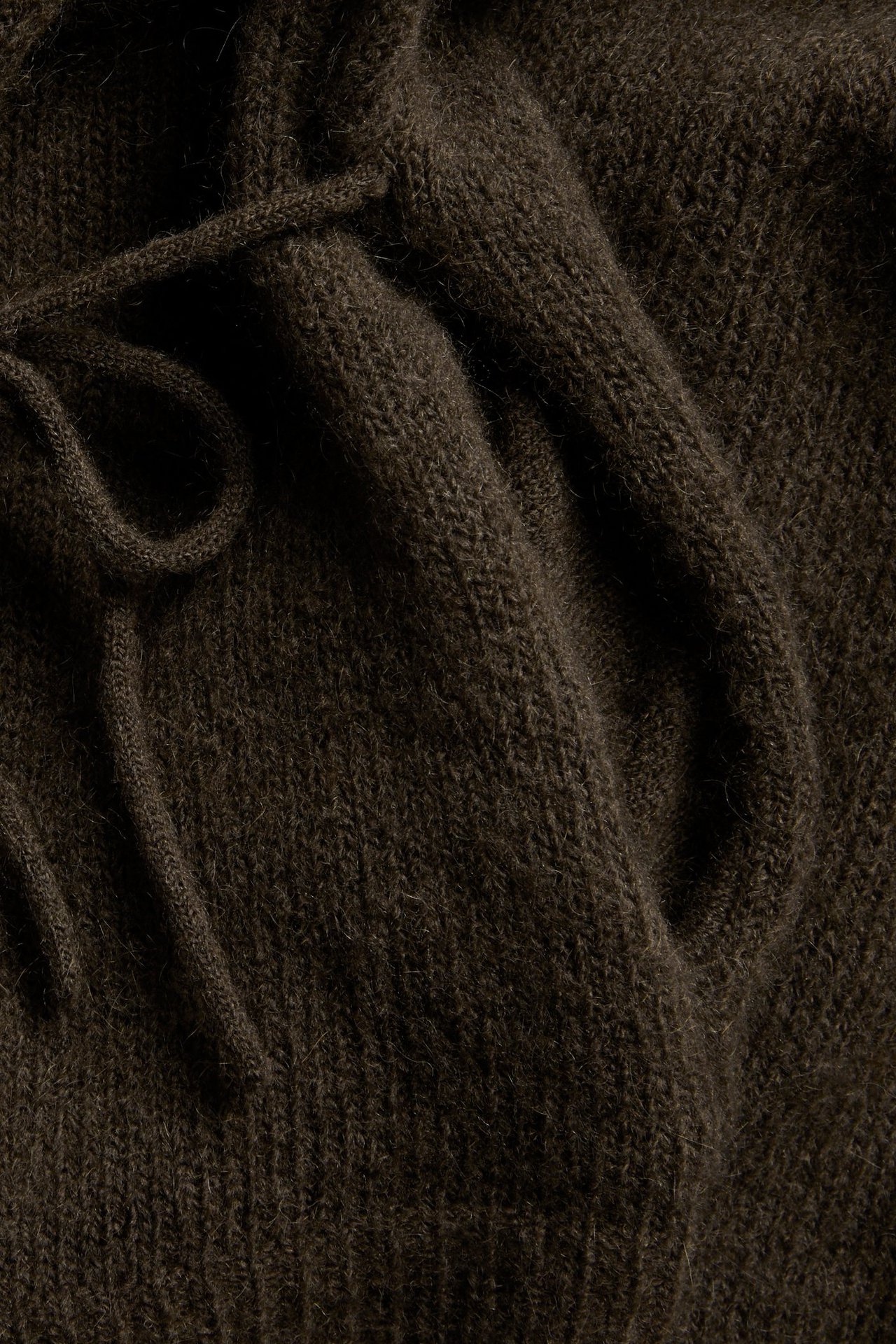Lähikuva ruskeasta, yksivärisestä villasekoiteneuletakista, jossa on solmittavat nauhat.