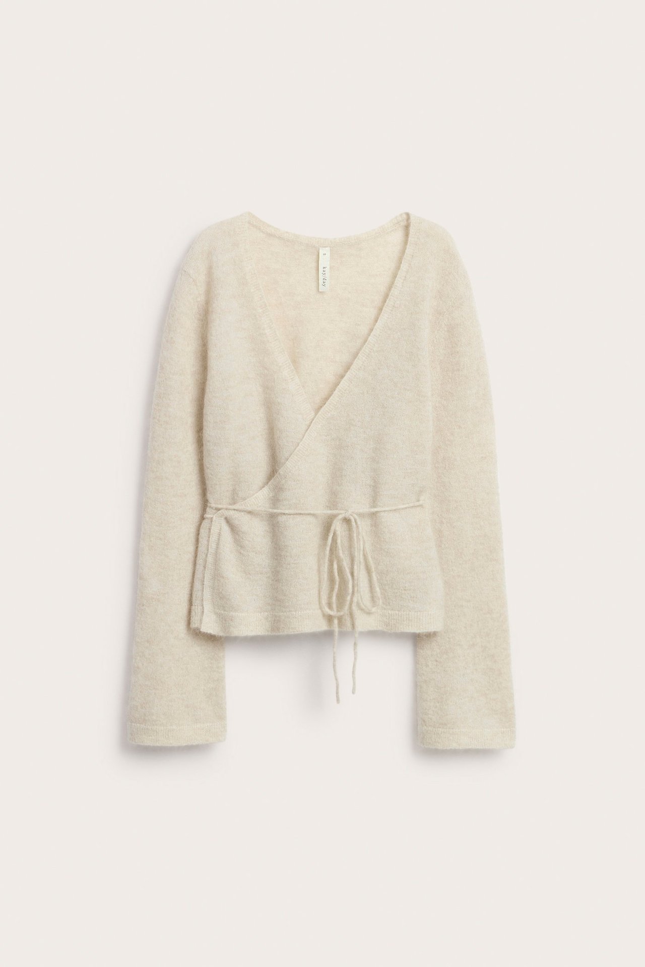 Edestäpäin, vaalea ohut villasekoite-kietaisuneuletakki solmimisnauhoilla ja leveillä hihansuilla.