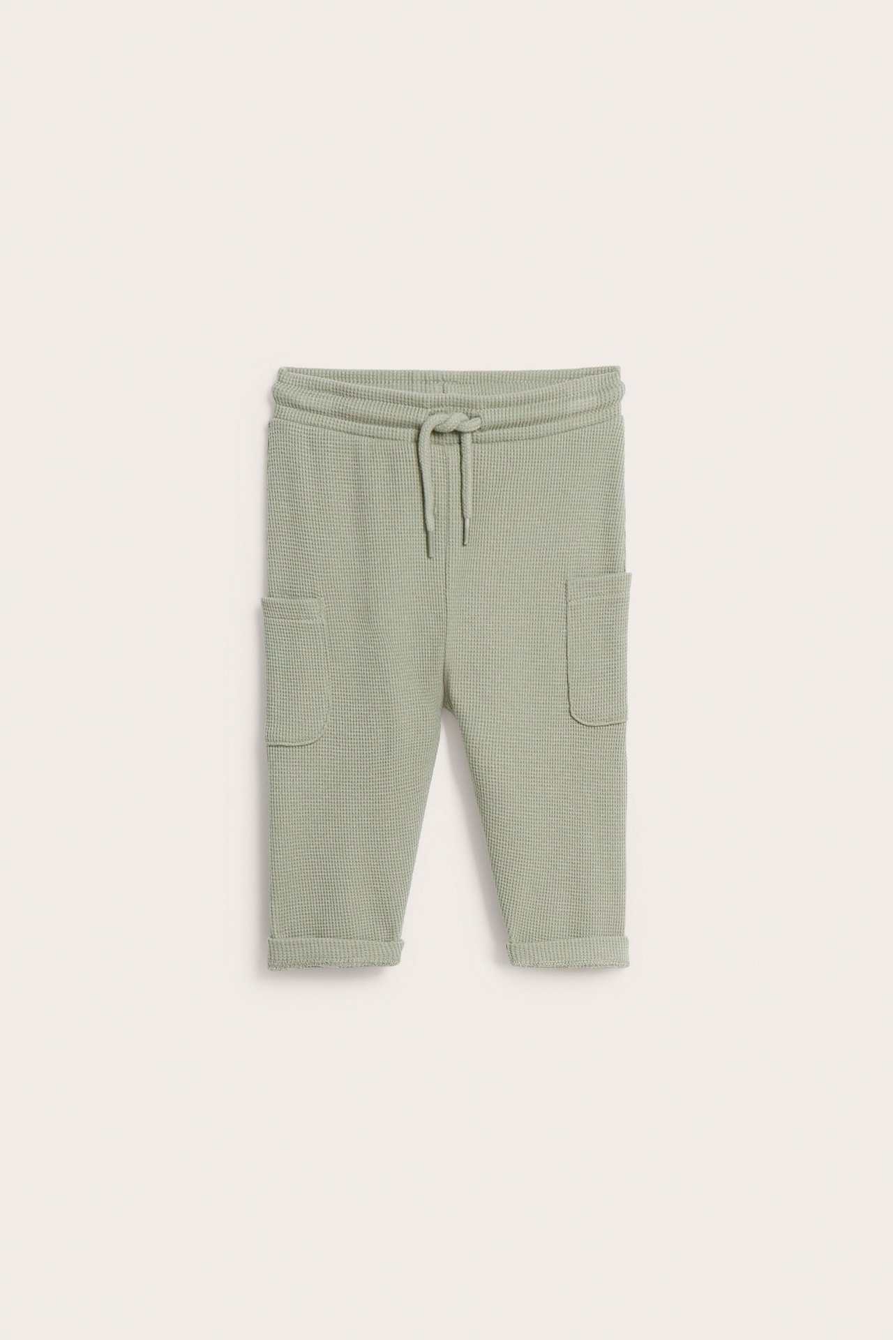 Edestäpäin vaaleanvihreät vauvan vohvelihousut, joissa nyörivyötärö ja kaksi sivutaskua.