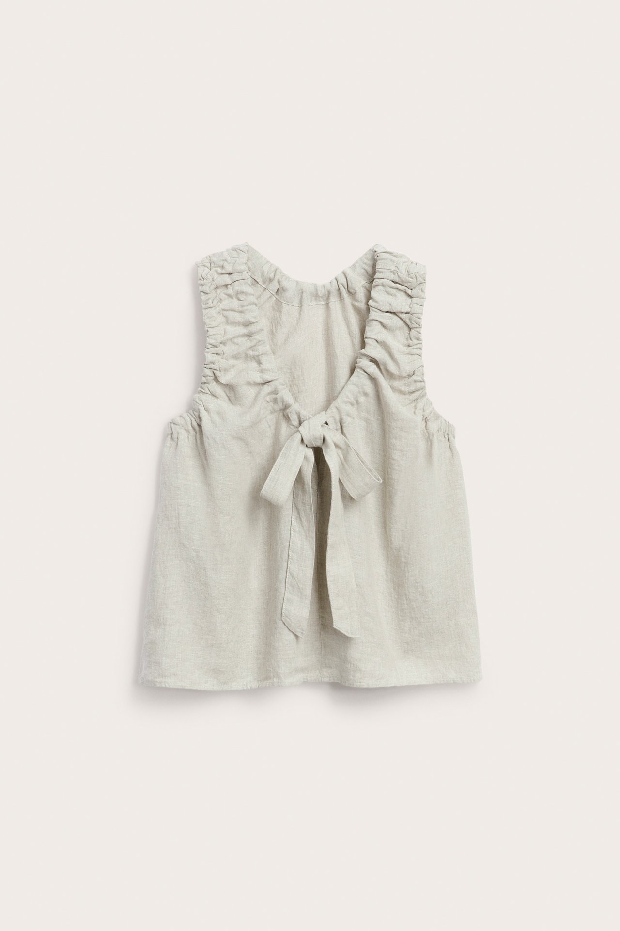 Widok z przodu beżowego lnianego topu z marszczonymi ramiączkami i wiązaniem przy dekolcie.