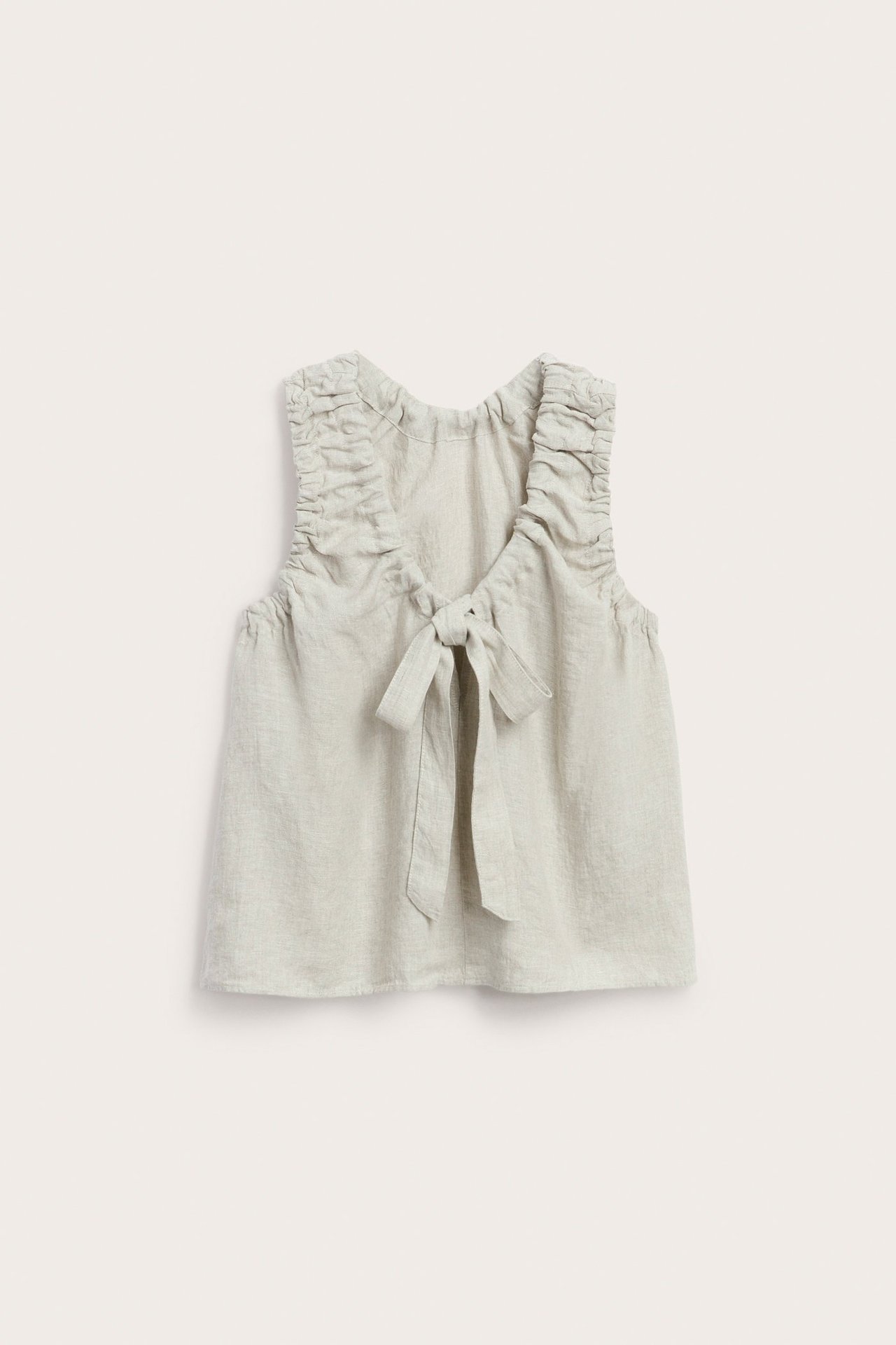 Widok z przodu beżowego lnianego topu z marszczonymi ramiączkami i wiązaniem przy dekolcie.