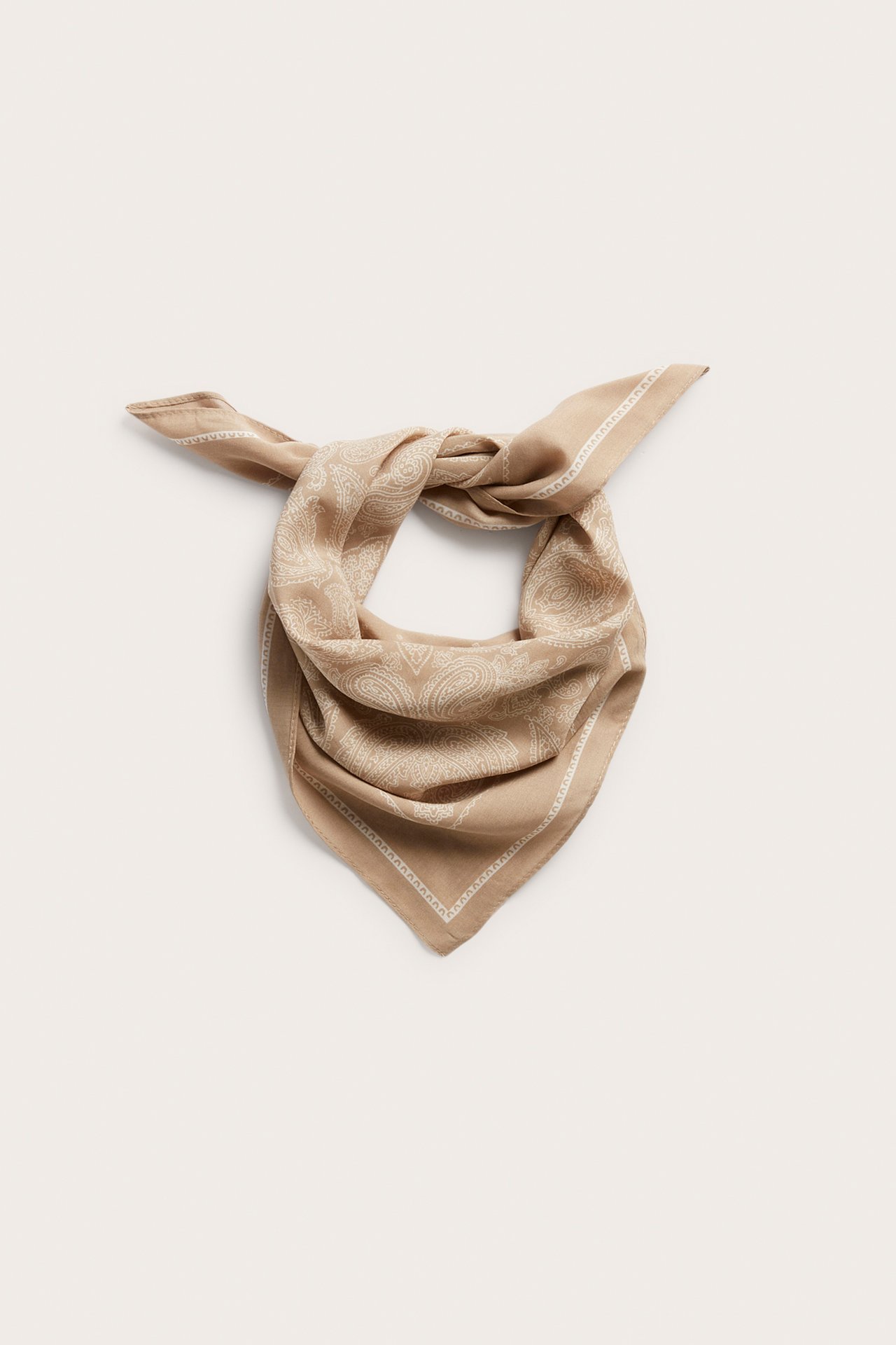 Edestäpäin kuvattu beige paisley-kuvioinen neliöhuivi, solmittuna.