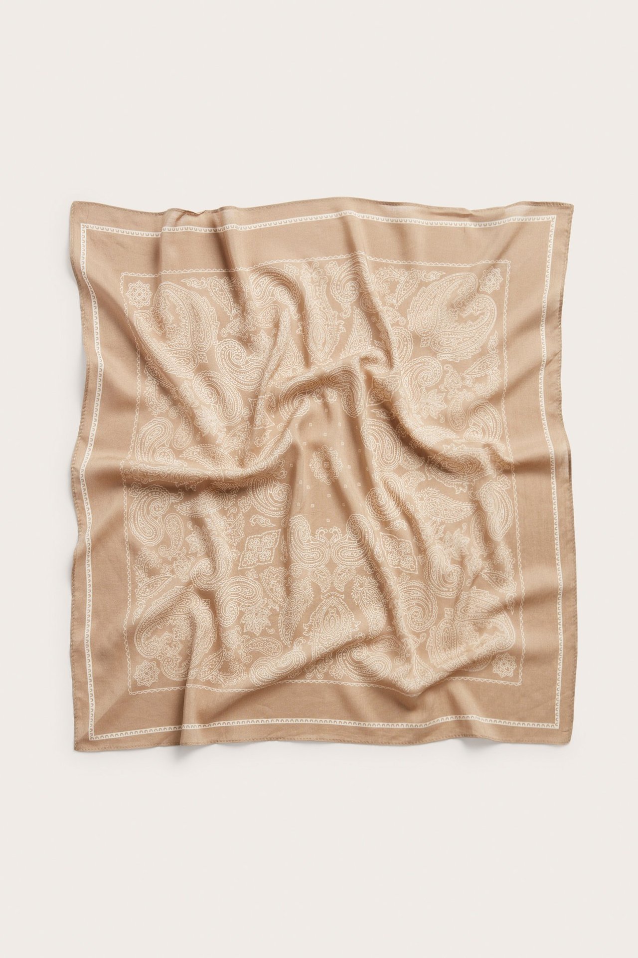 Ylhäältä kuvattu beigepohjainen neliöhuivi valkoisella paisleykuviolla.