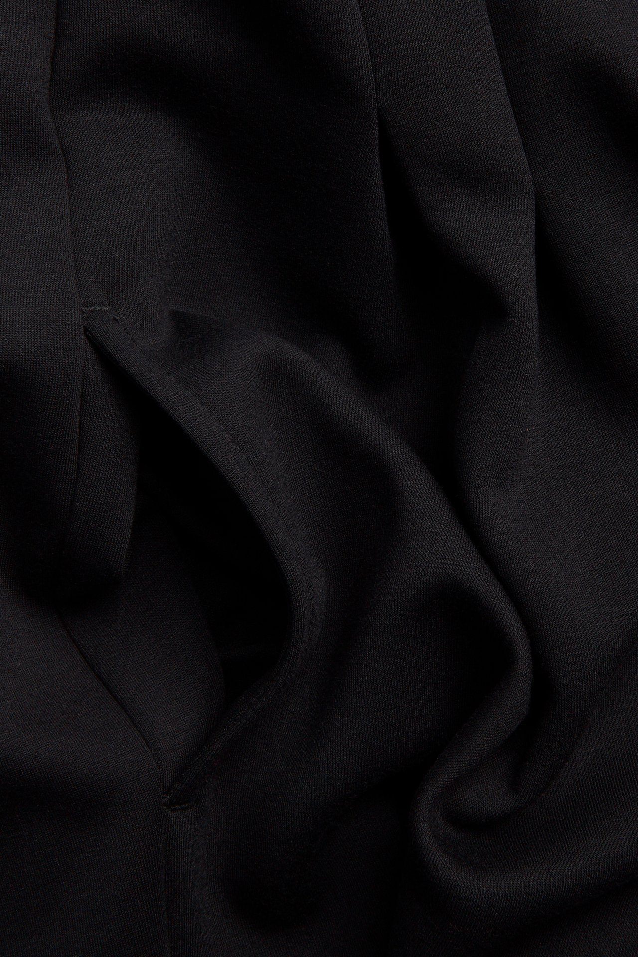 Närbild av en svart jerseyklänning, som visar en sidficka.