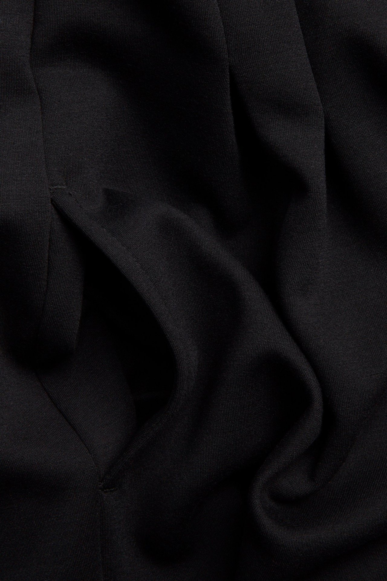 Närbild av en svart jerseyklänning, som visar en sidficka.