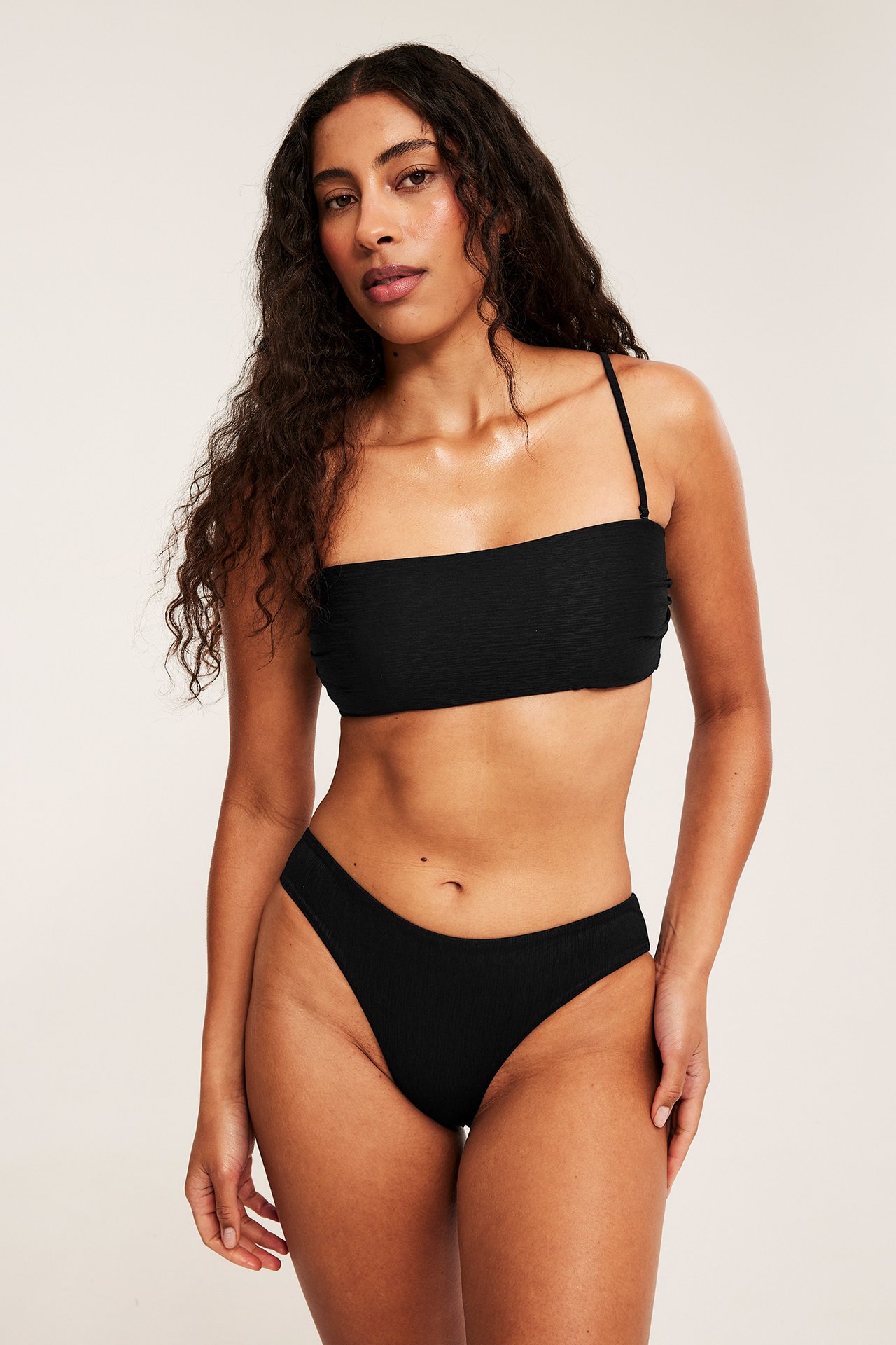 Edestä, nainen mustassa kuvioidussa topatussa bandeau-bikinitopissa ja yhteensopivissa bikinialaosissa.