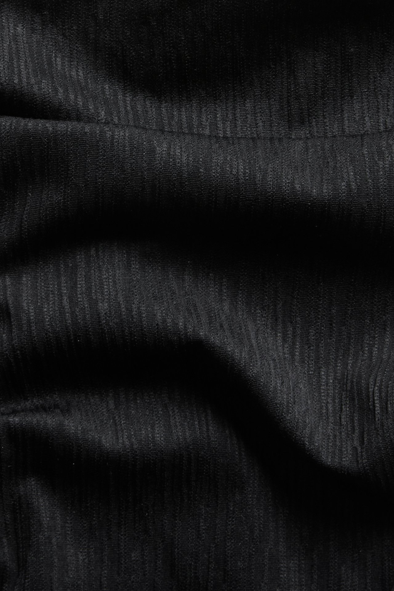 Nærbilde av svart teksturert brazilian high leg bikinitruse-stoff med subtile vertikale striper.