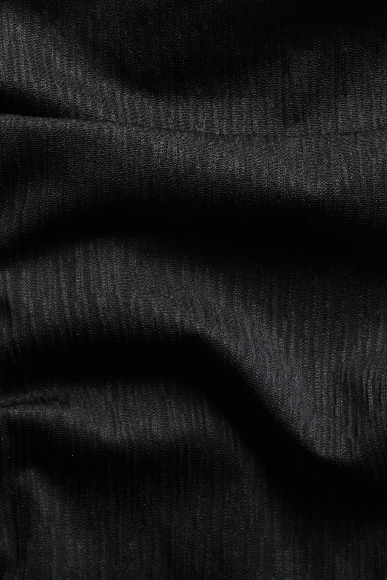 Nærbilde av svart teksturert brazilian high leg bikinitruse-stoff med subtile vertikale striper.