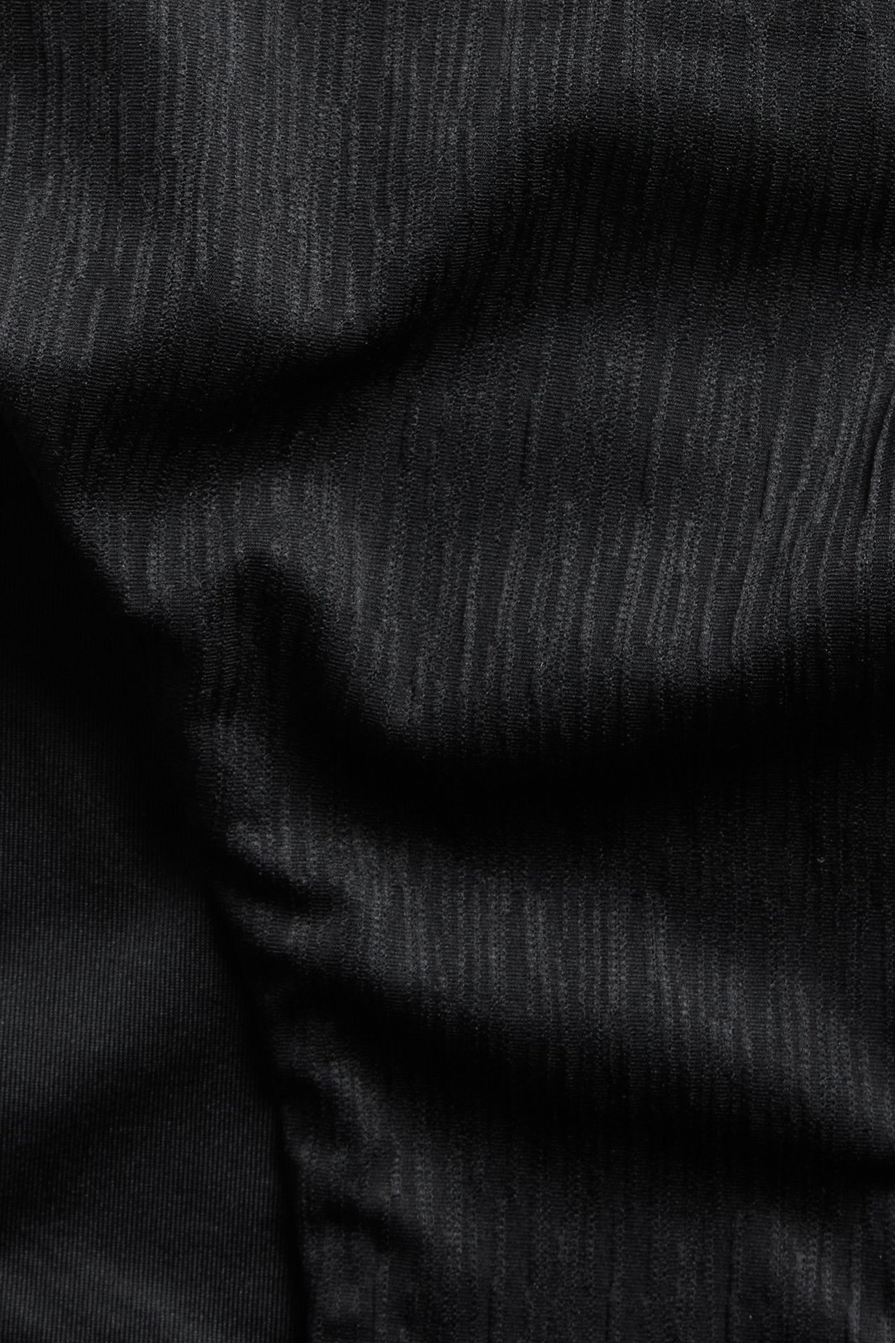 Lähikuva mustasta strukturoidusta bikinialaosan kankaasta.