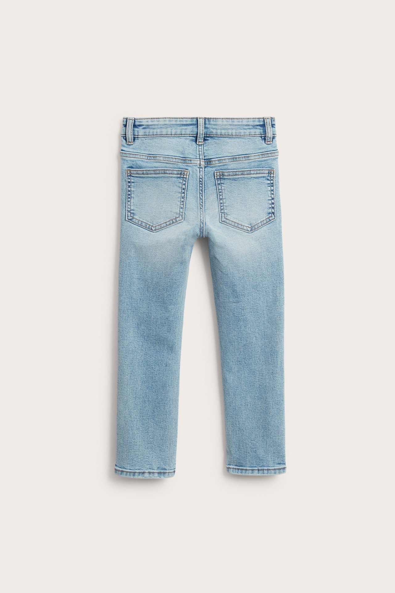Tylny widok jasnoniebieskich jeansów superstretch slim-fit dla dzieci z tylnymi kieszeniami.
