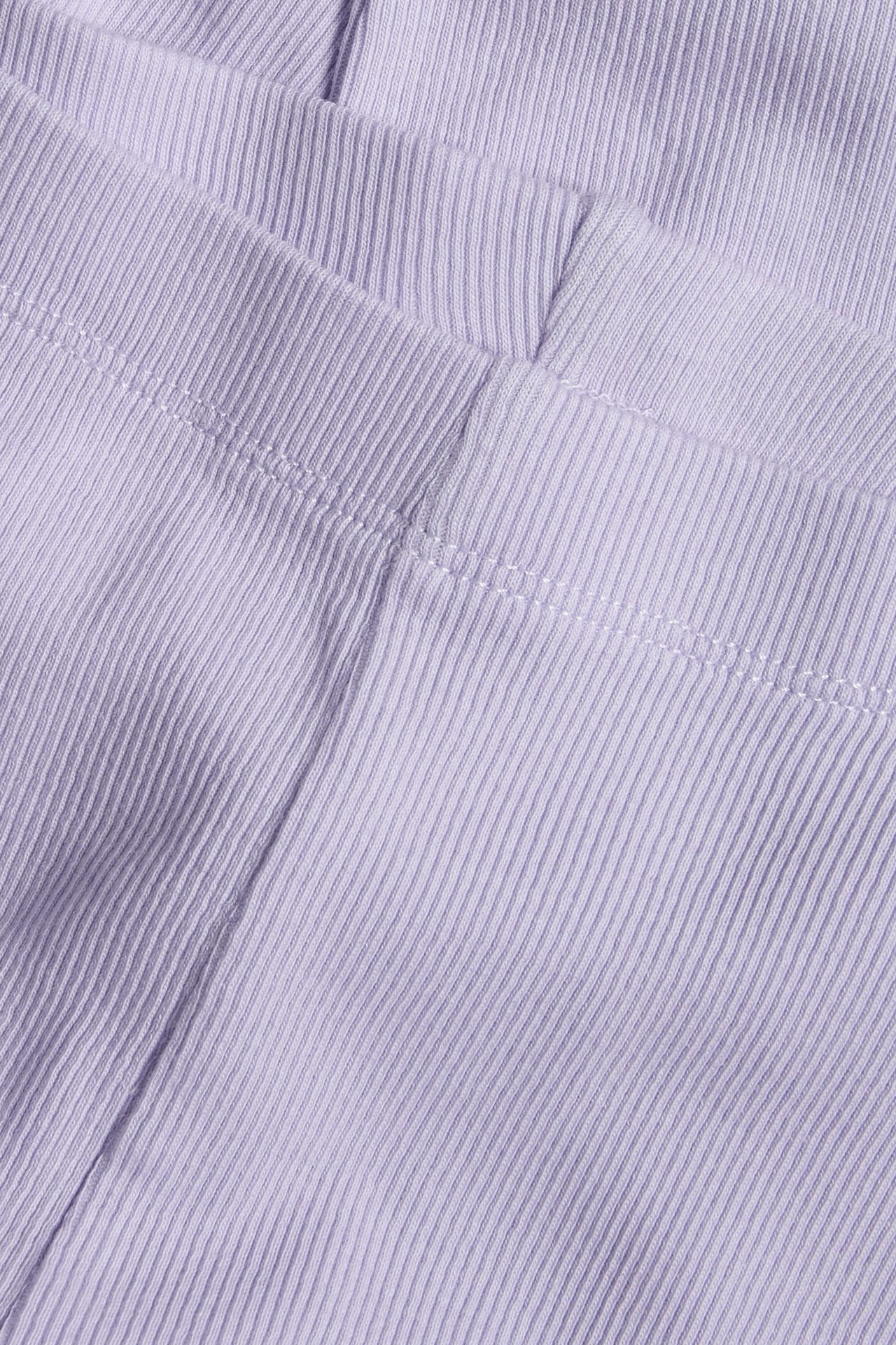 Zbliżenie na jasnofioletowe legginsy w prążki, ukazujące teksturę materiału i białe szwy.