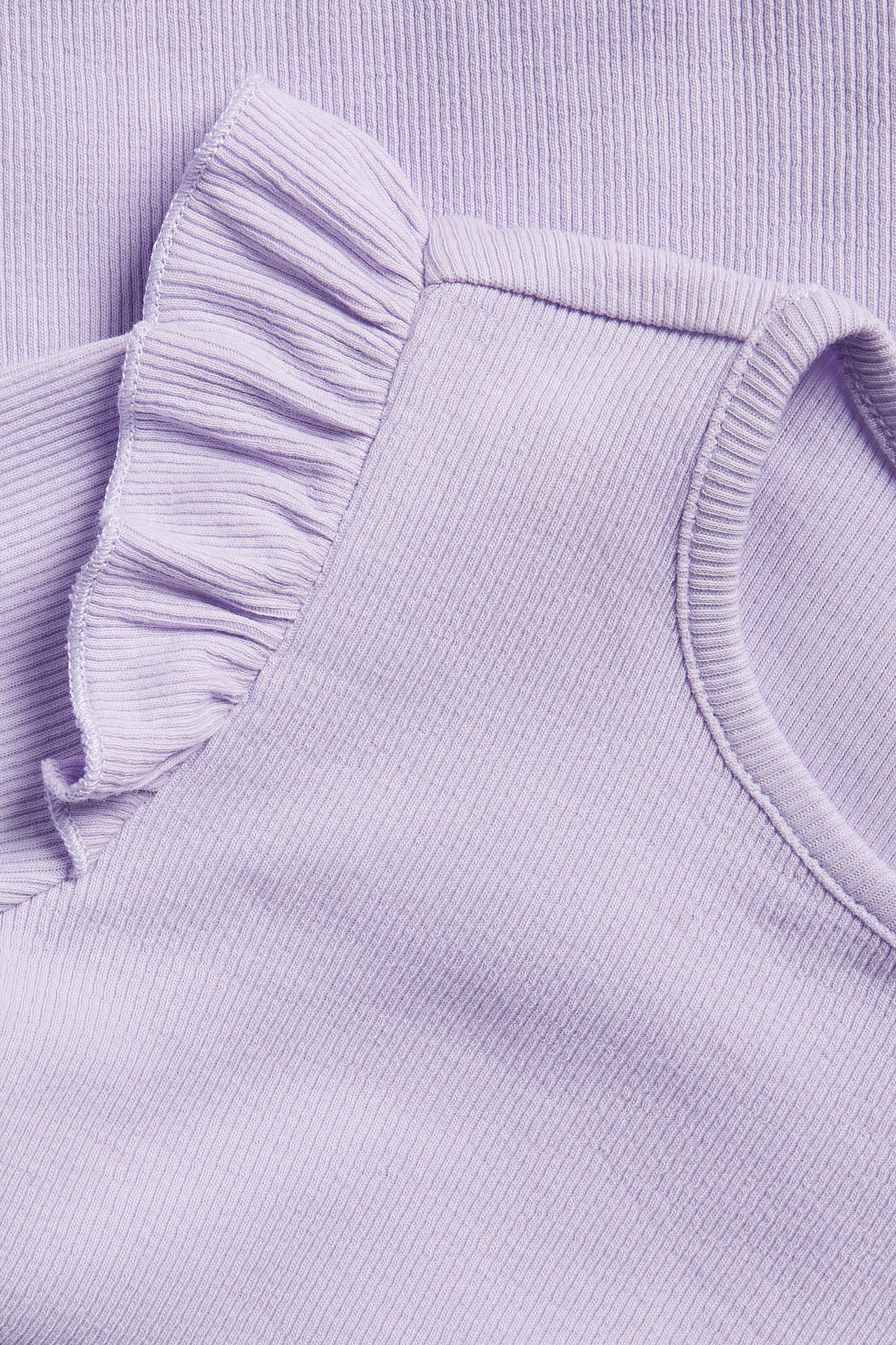 Zbliżenie jasnofioletowego prążkowanego topu z długim rękawem i falbanką na ramieniu.