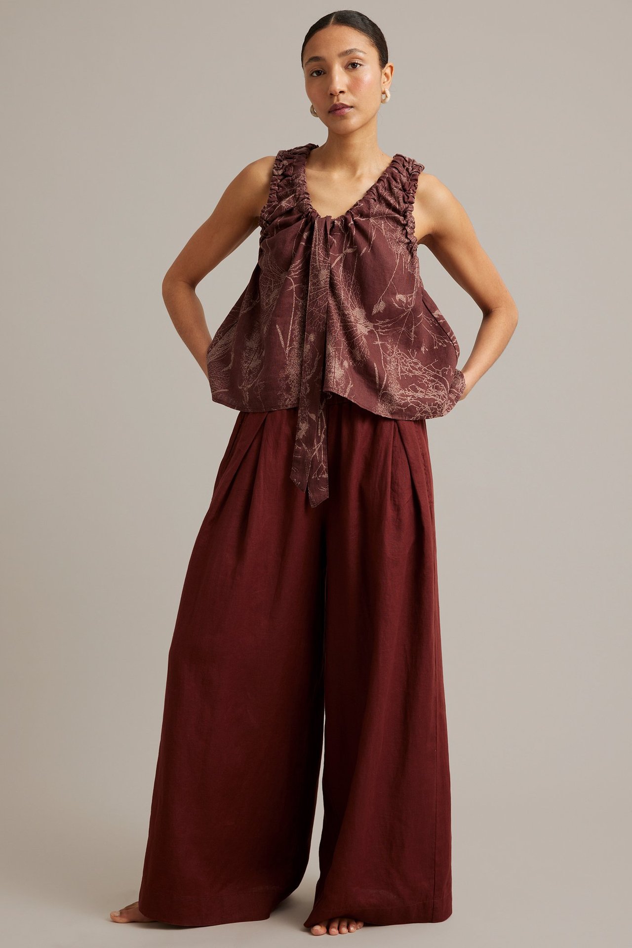 Kvinna i vinröd blommig linnetopp med dragsko och matchande vida byxor, frontvy.