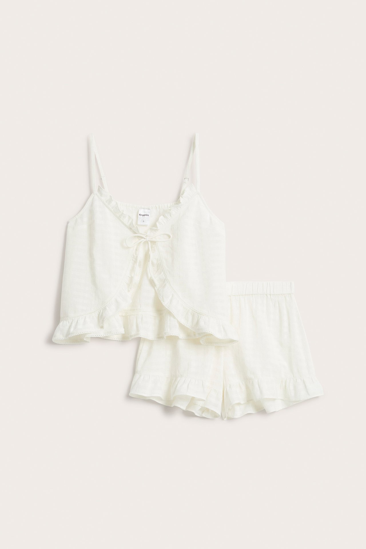 Frontvisning: Offwhite pyjamasett i strukturert bomull, volangkantet topp med knytebånd og matchende shorts.