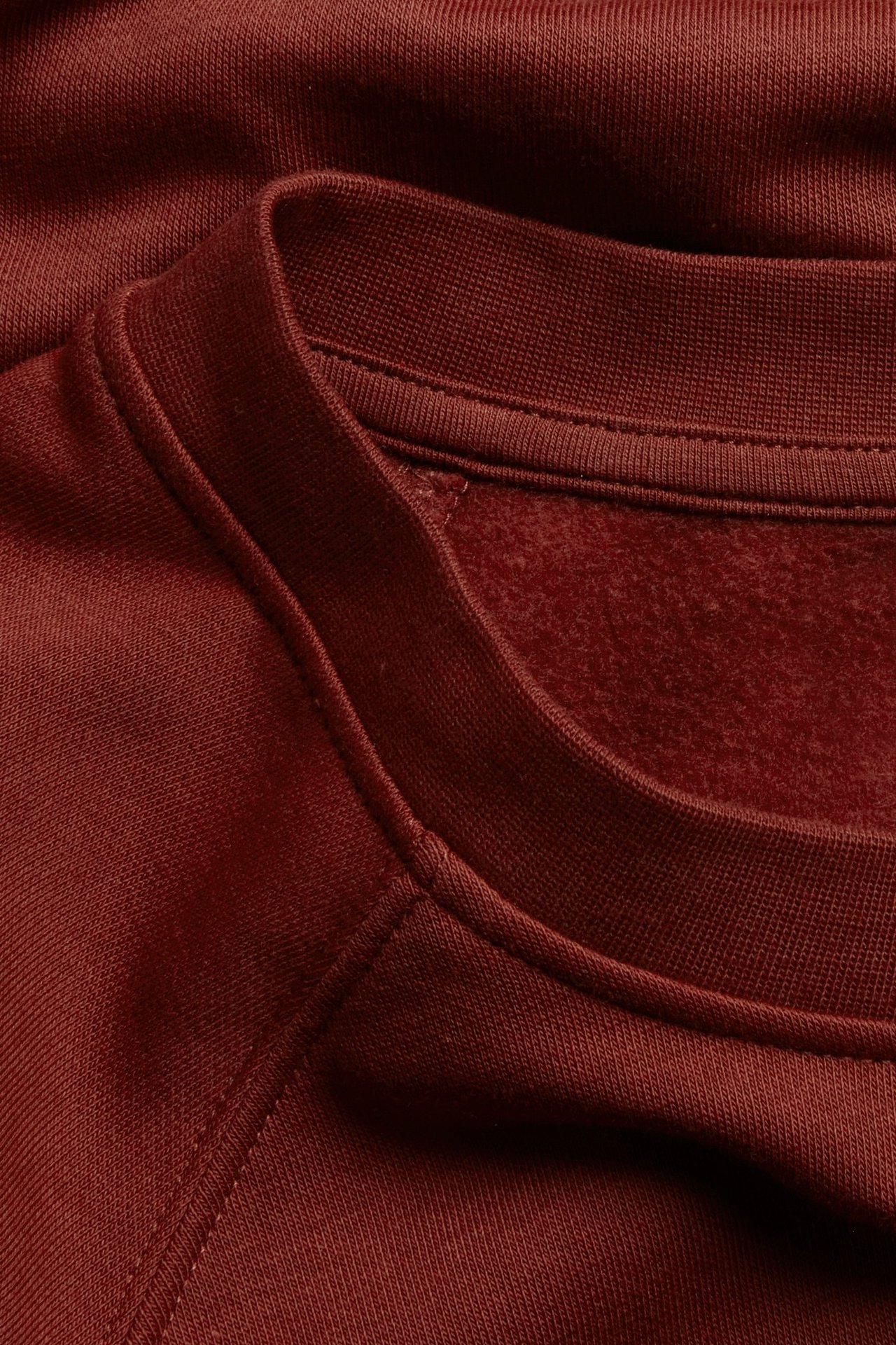 Zbliżenie czerwonego, krótkiego swetra z mieszanki bawełny z prążkowanym okrągłym dekoltem.