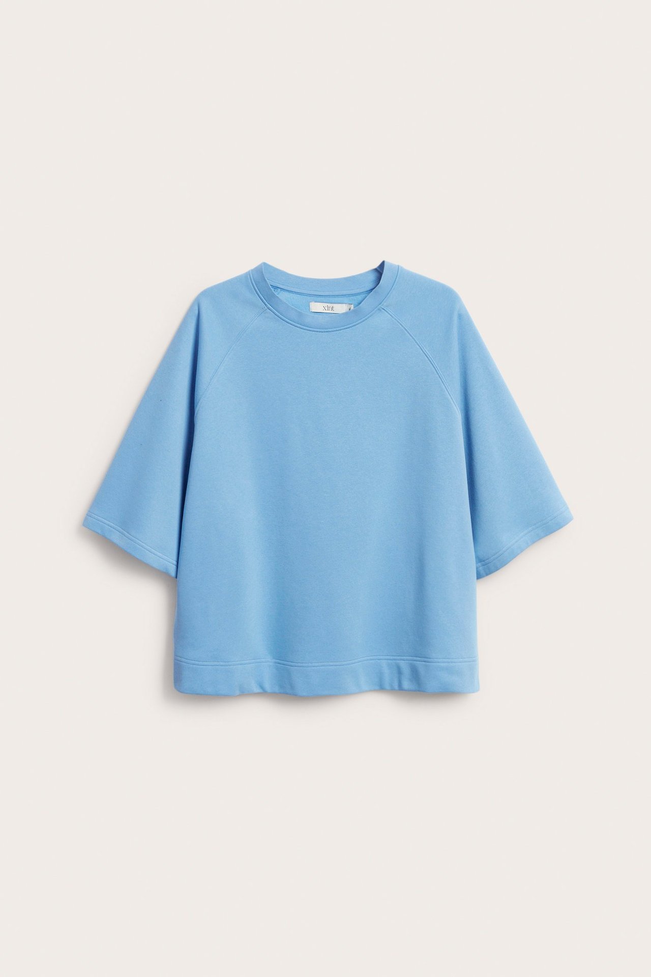 Edestäpäin sininen, lyhythihainen, yksivärinen collegepaita, jossa on rento istuvuus ja resorihelma.