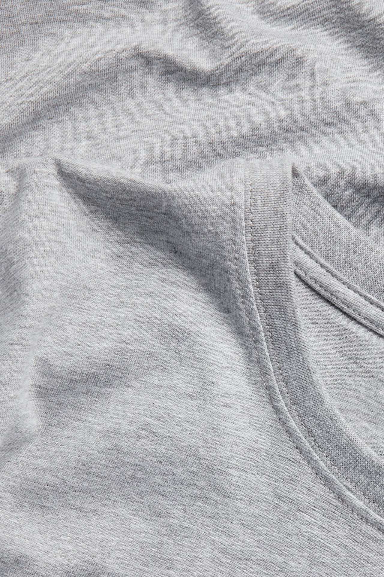 Zbliżenie szarego melanżowego t-shirtu z widoczną fakturą tkaniny i szwami dekoltu.