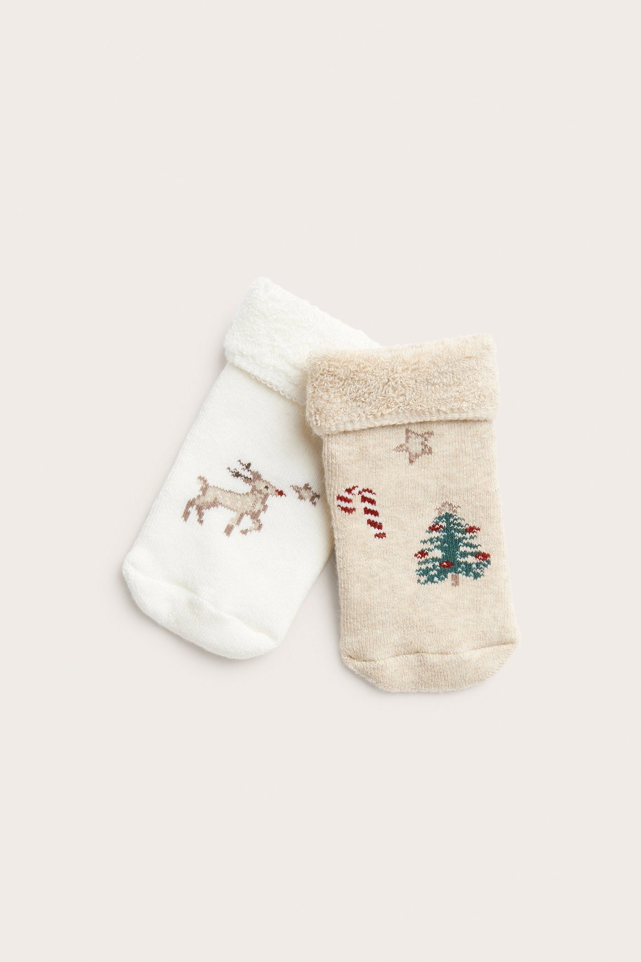 Forfra to frotte sokker: en offwhite med reinmotiv, en beige med juletre.