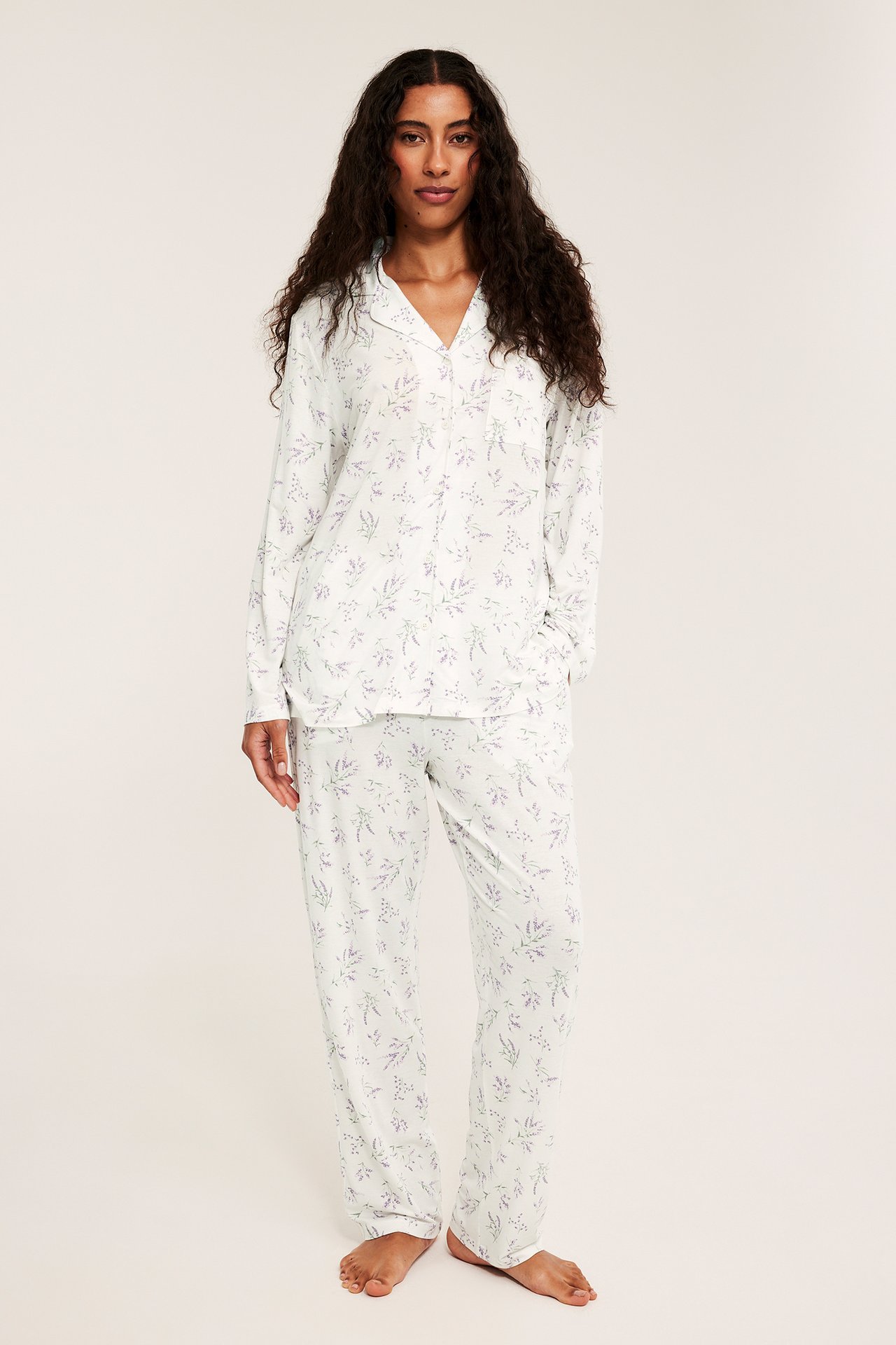 Etukuva naisesta vaaleanlila kuvioidussa lyocell-pyjamassa: napitettu paita ja löysät housut.