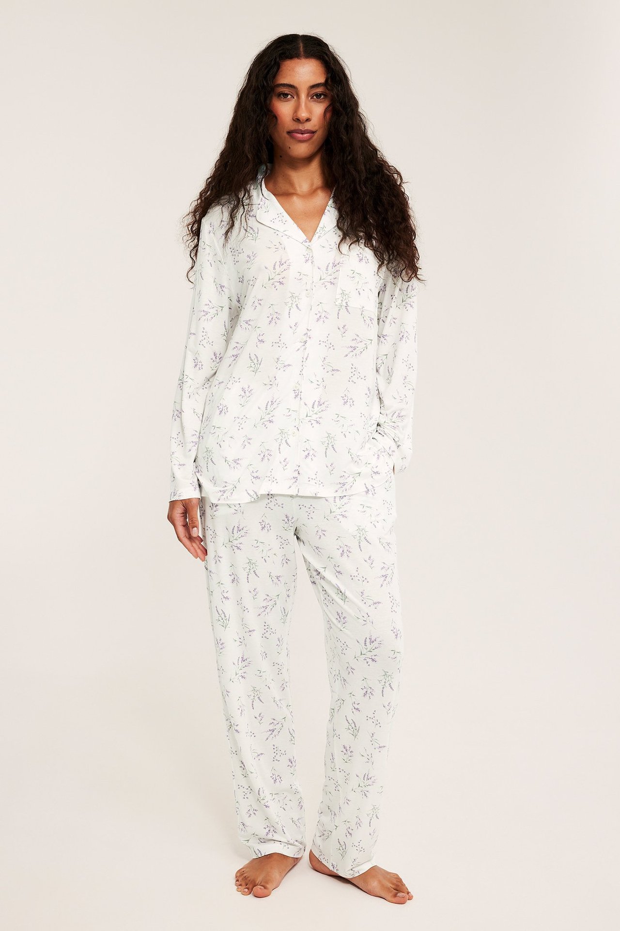 Etukuva naisesta vaaleanlila kuvioidussa lyocell-pyjamassa: napitettu paita ja löysät housut.
