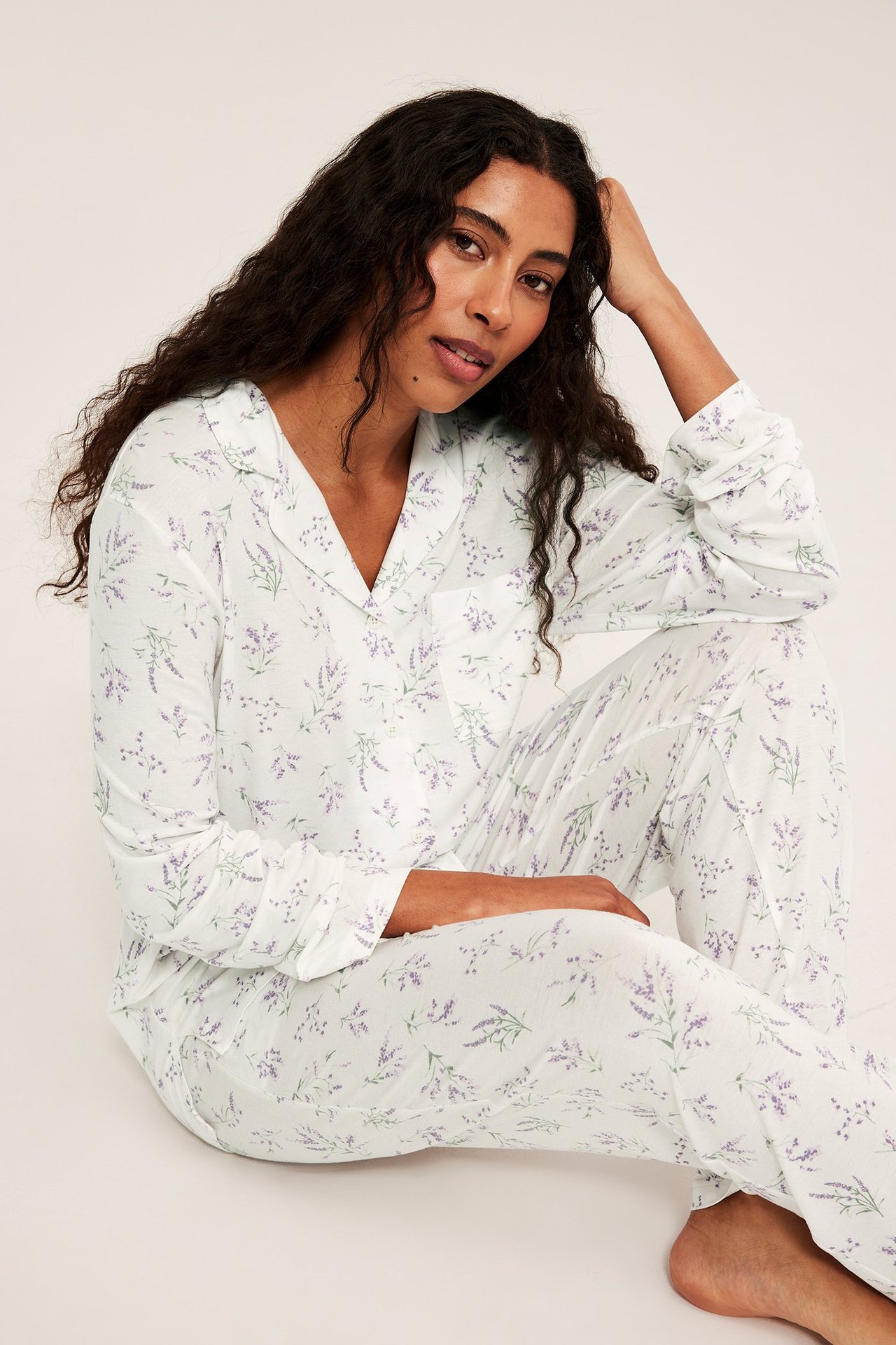 Edestä, nainen vaalealilassa kuviollisessa lyocell-pyjamasetissä; kauluspaita ja suorat housut.